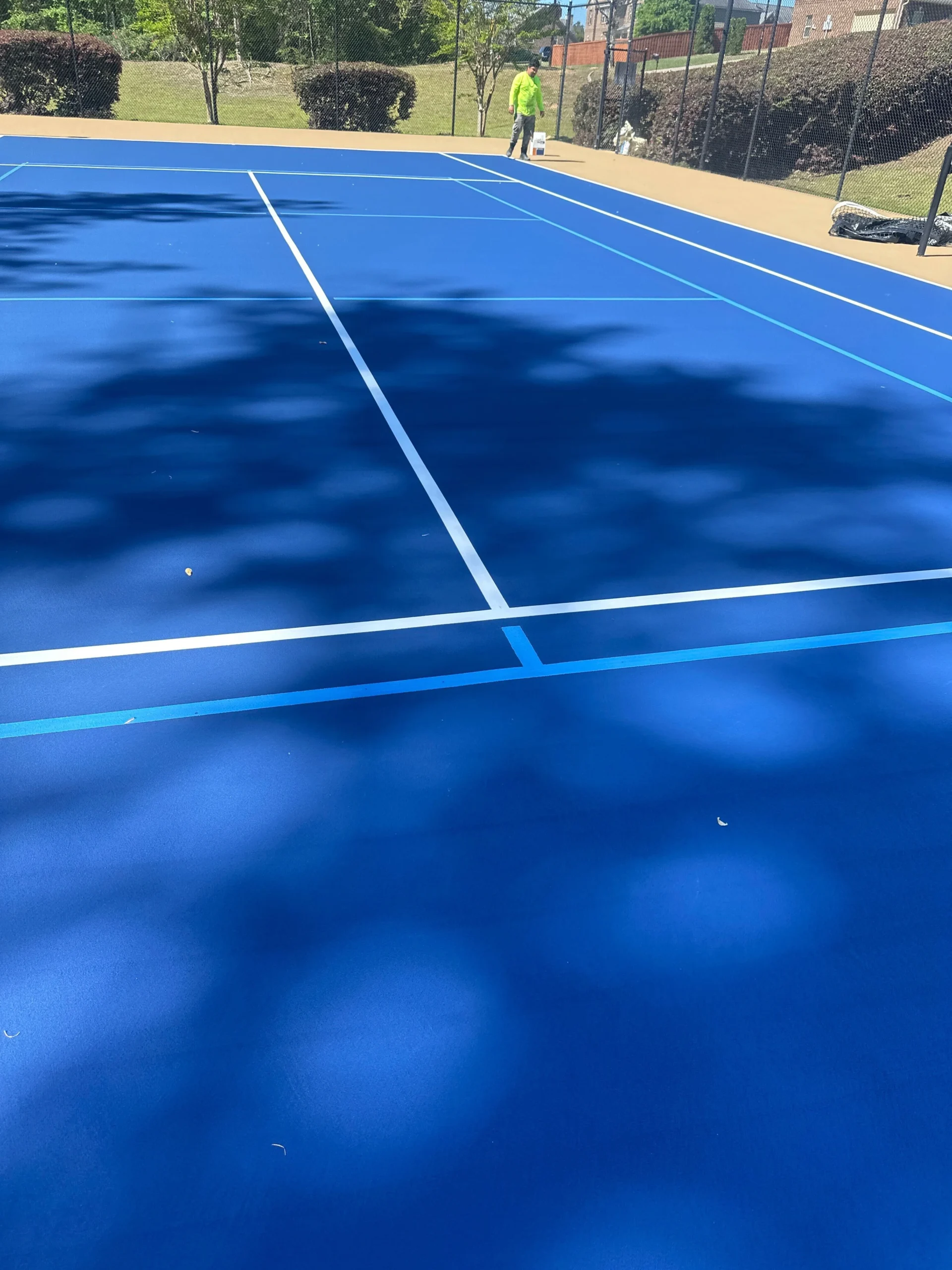Pro Track & Tennis crew member finishing court striping on resurfaced tennis court in Fort Mitchell, AL
