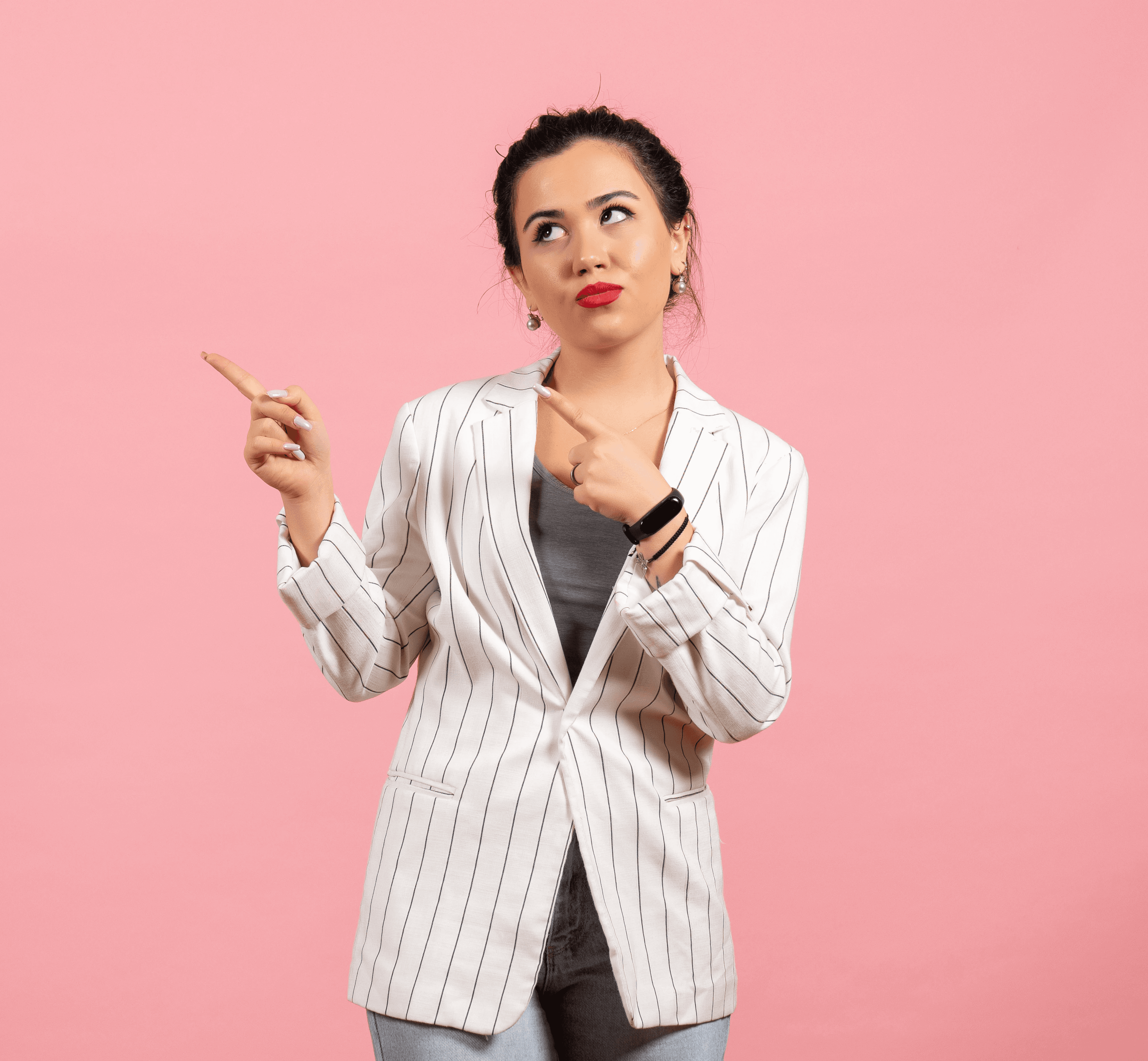 Smiling young woman with long hair standing against a dark green background, holding a finger to her chin.