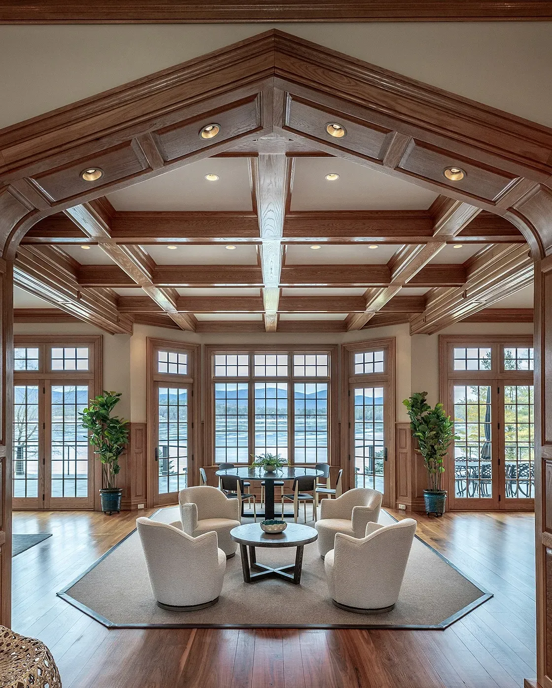 Spacious dining room with high wooden ceilings, large windows, and a long dining table surrounded by chairs.
