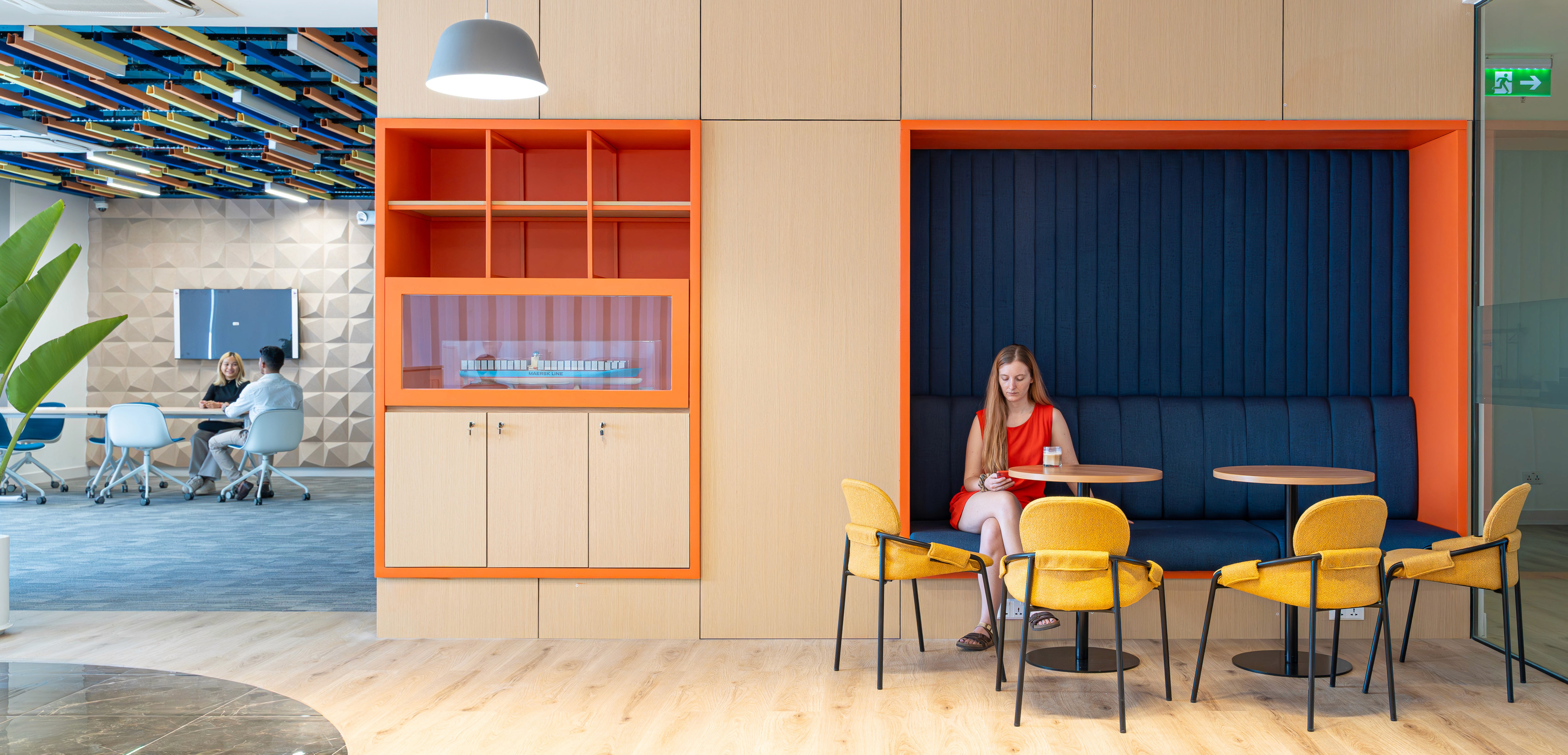 Breakout booth with integrated timber joinery, upholstered seating, and inset shelving creating semi-private collaboration within the open office