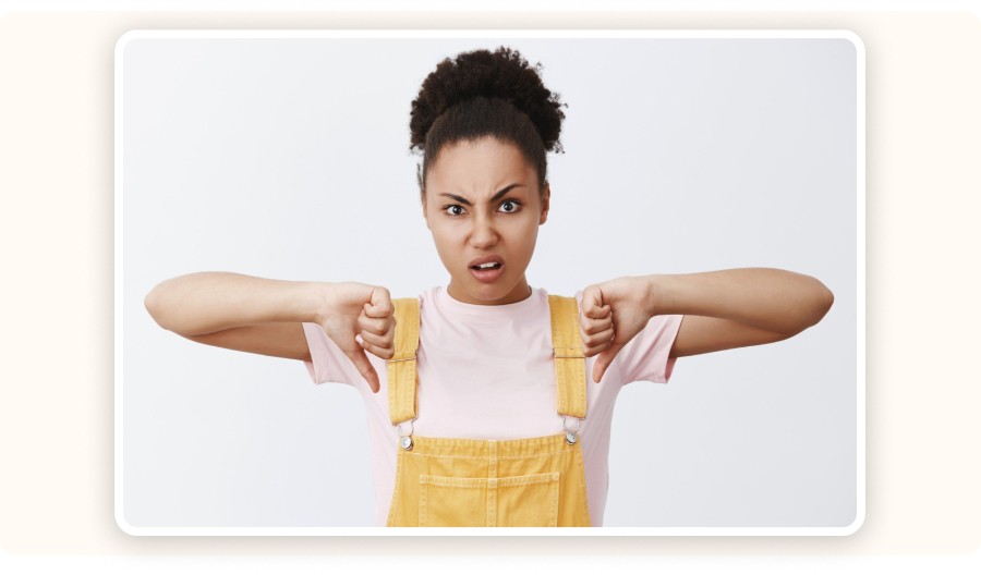 Woman showing thumbs down with frustrated expression on white background