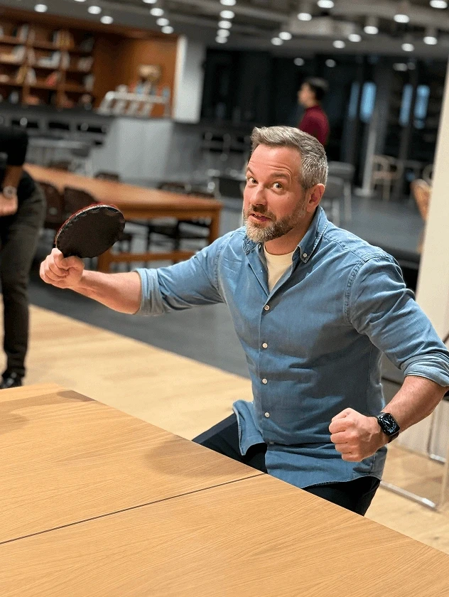 Team member playing table tennis in an office lounge.