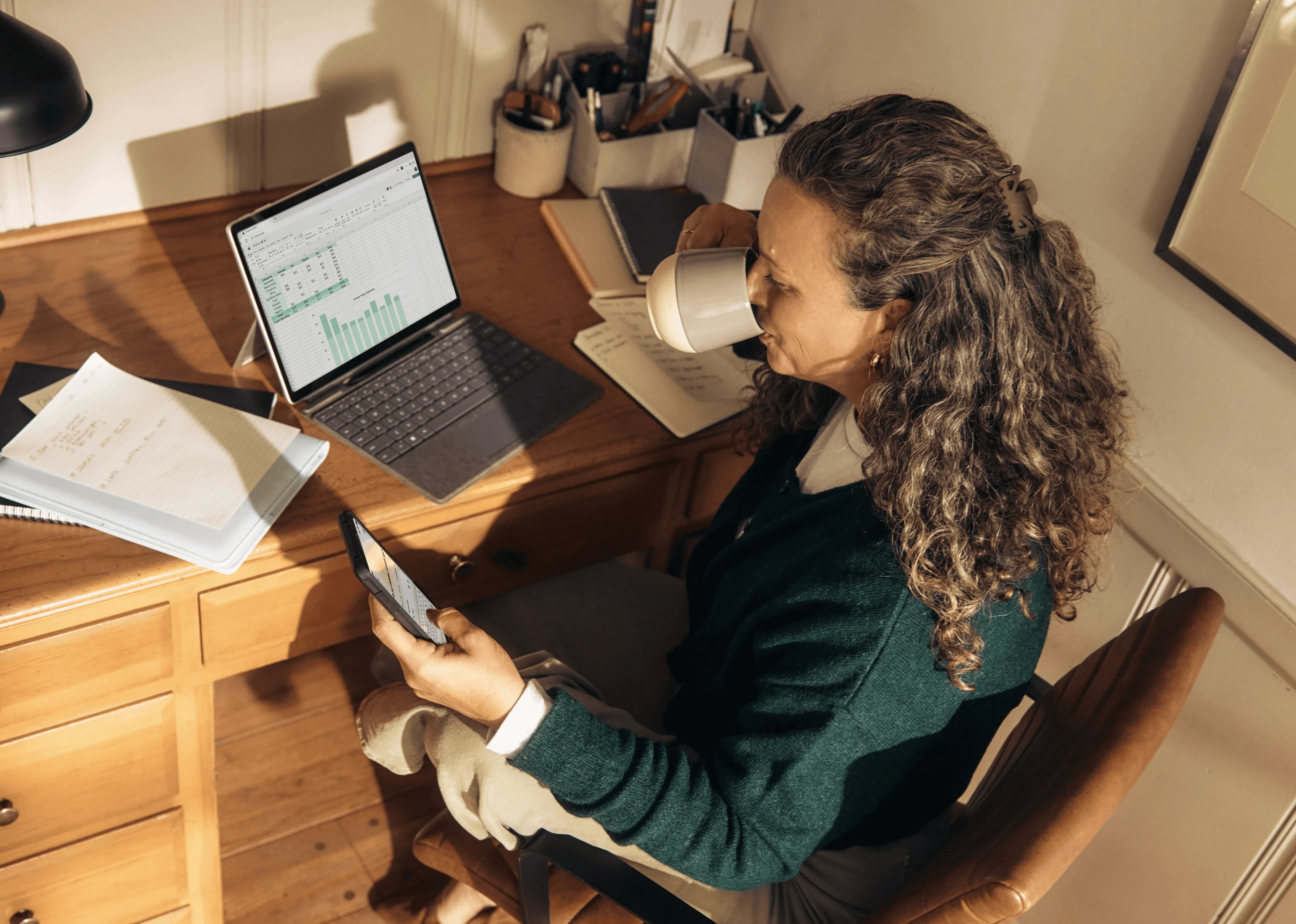 Woman working at a desk with laptop and tablet.