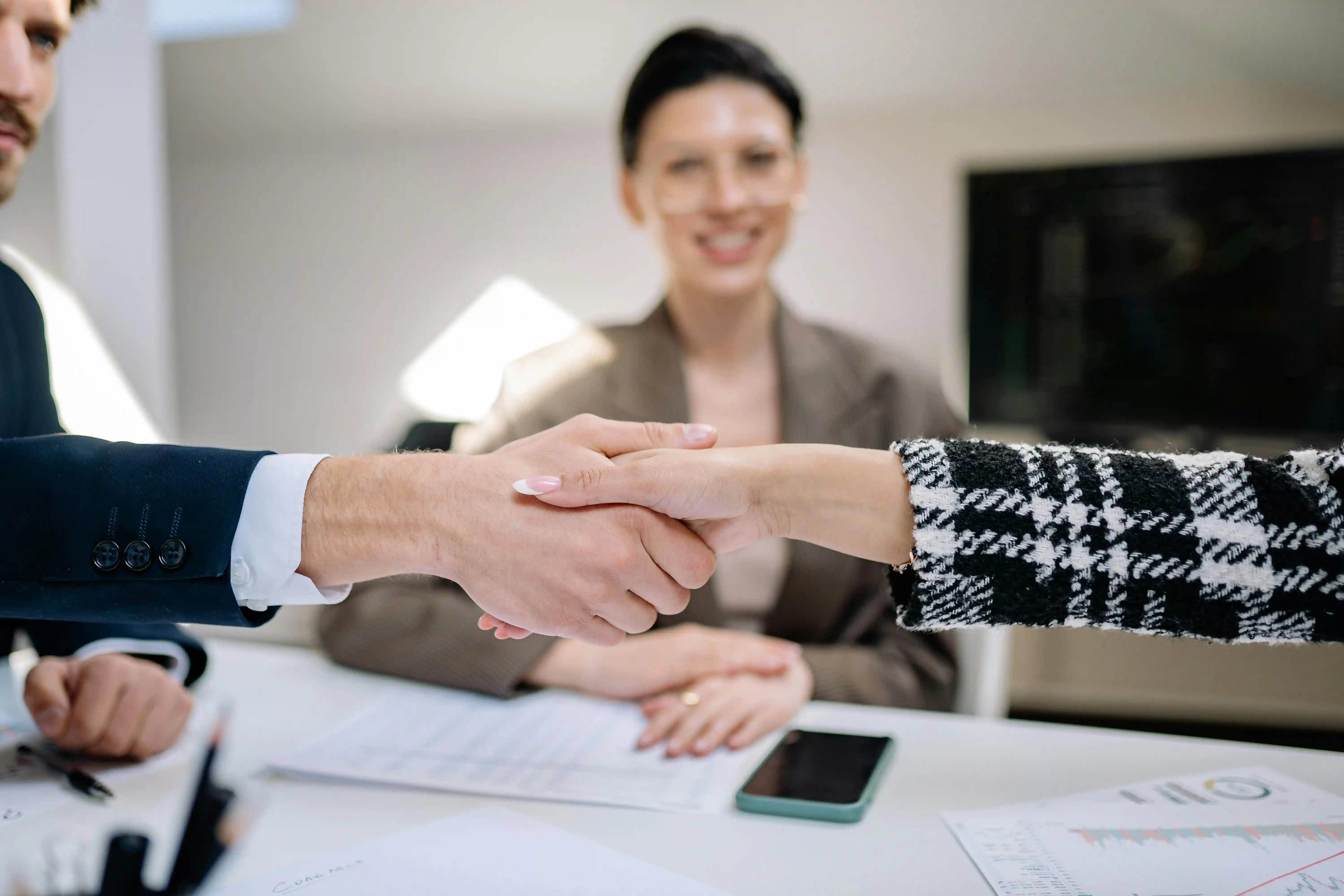 two people shaking hands in front of a laptop