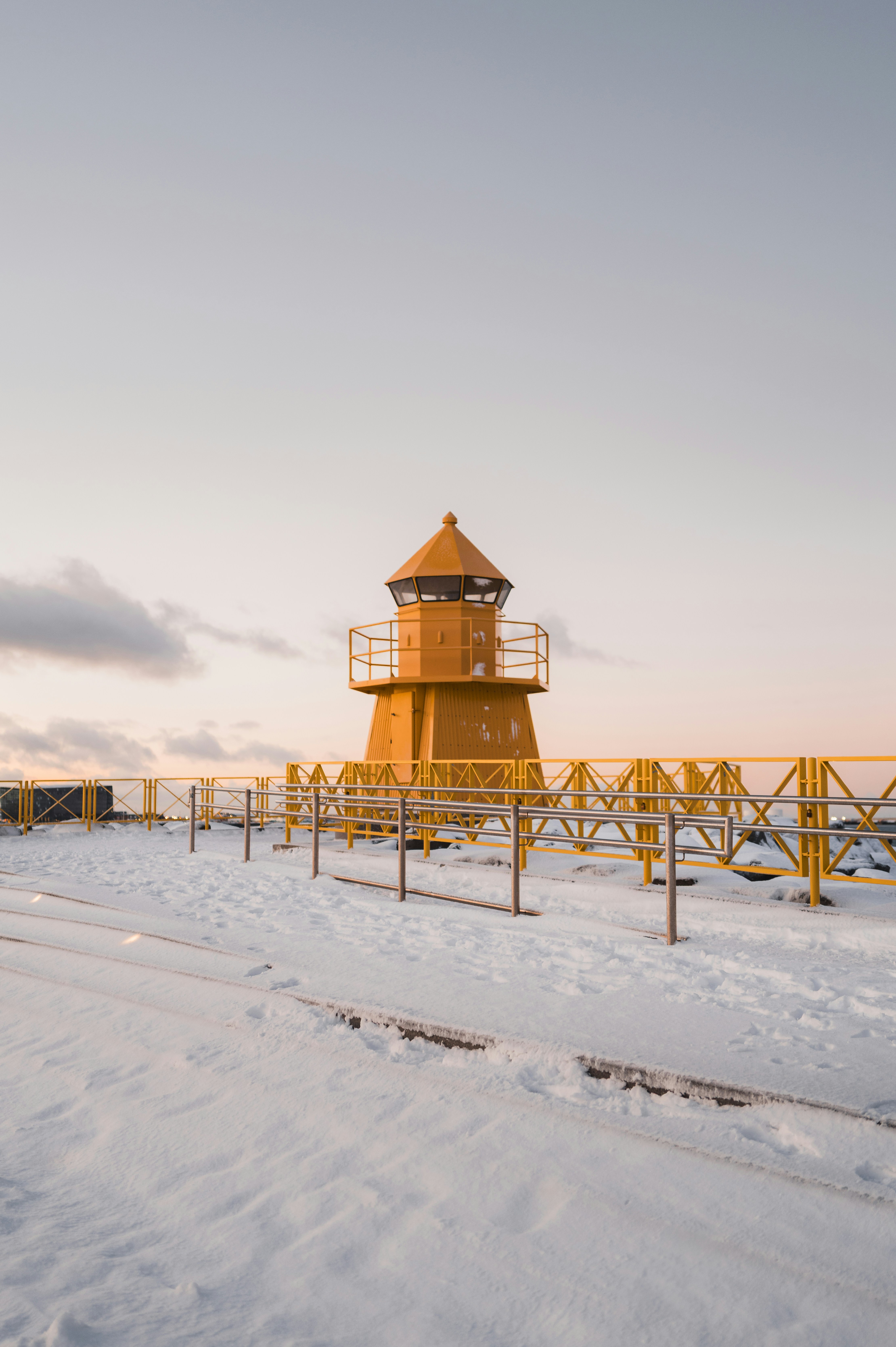 Yellow lighthouse on a snowy pier at dawn