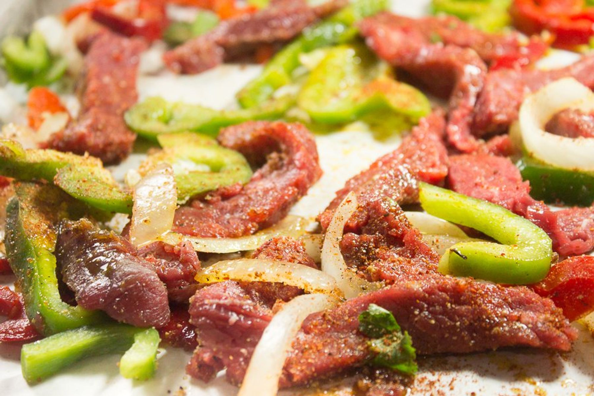 seasoned vegetables and steak on a baking sheet