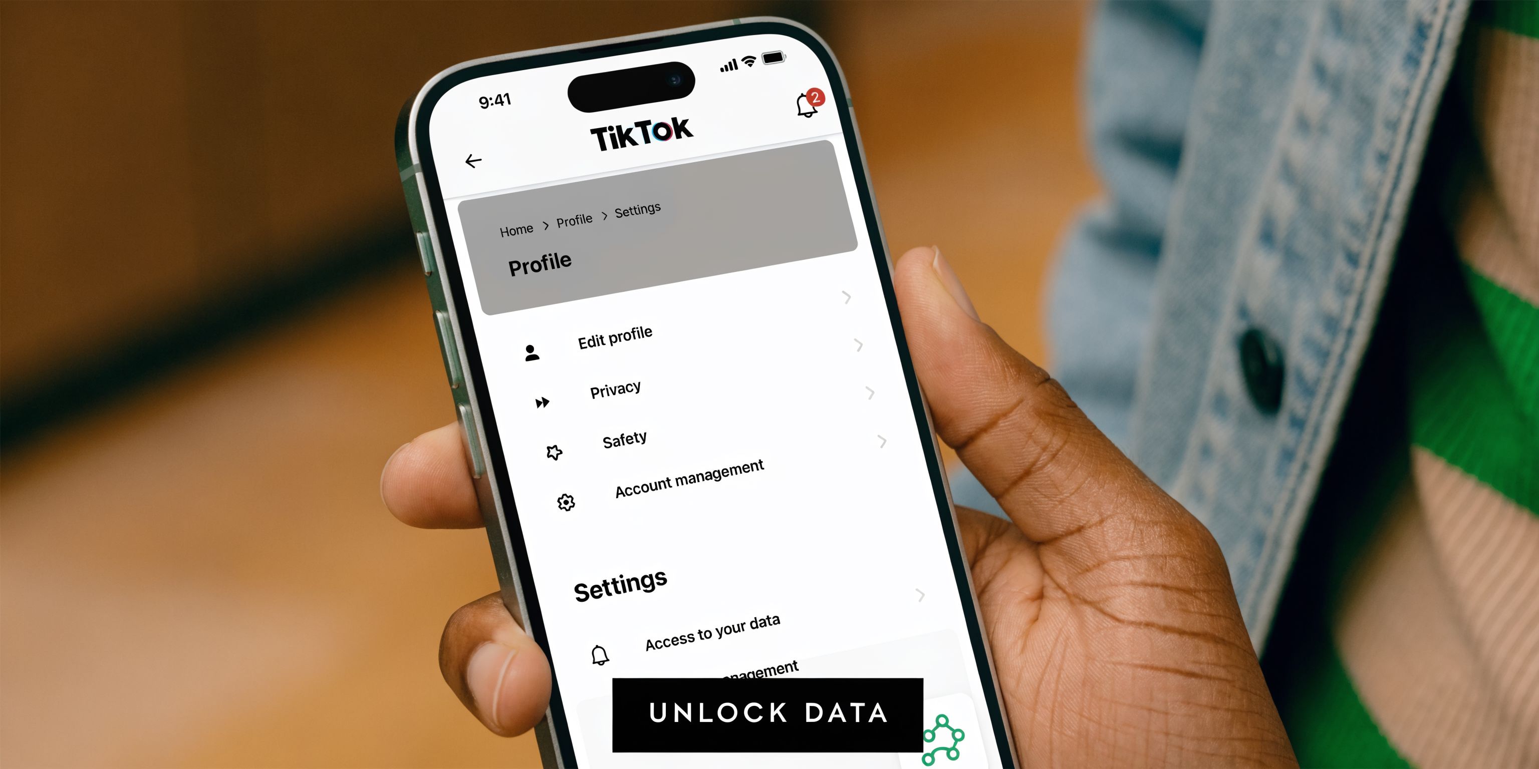 A close-up view of a hand holding a smartphone displaying the TikTok app profile settings menu.