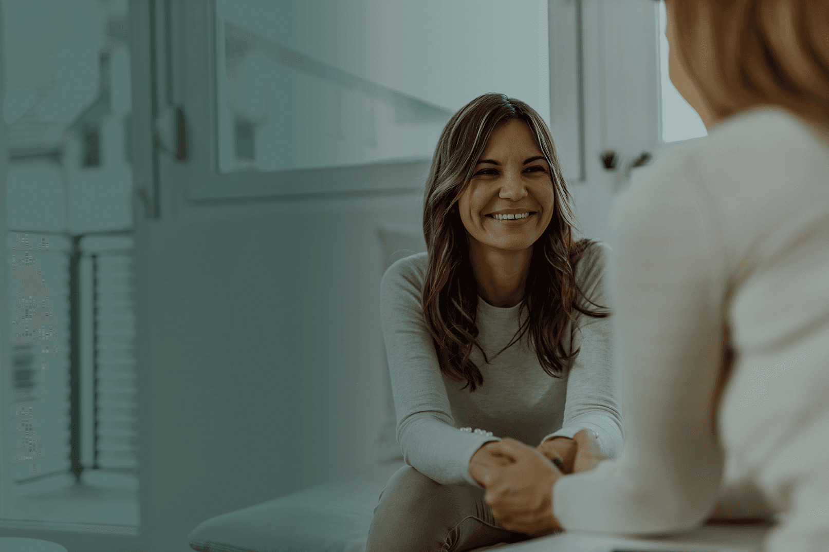 A doctor in white coat and stethescope smiling wide at a patient