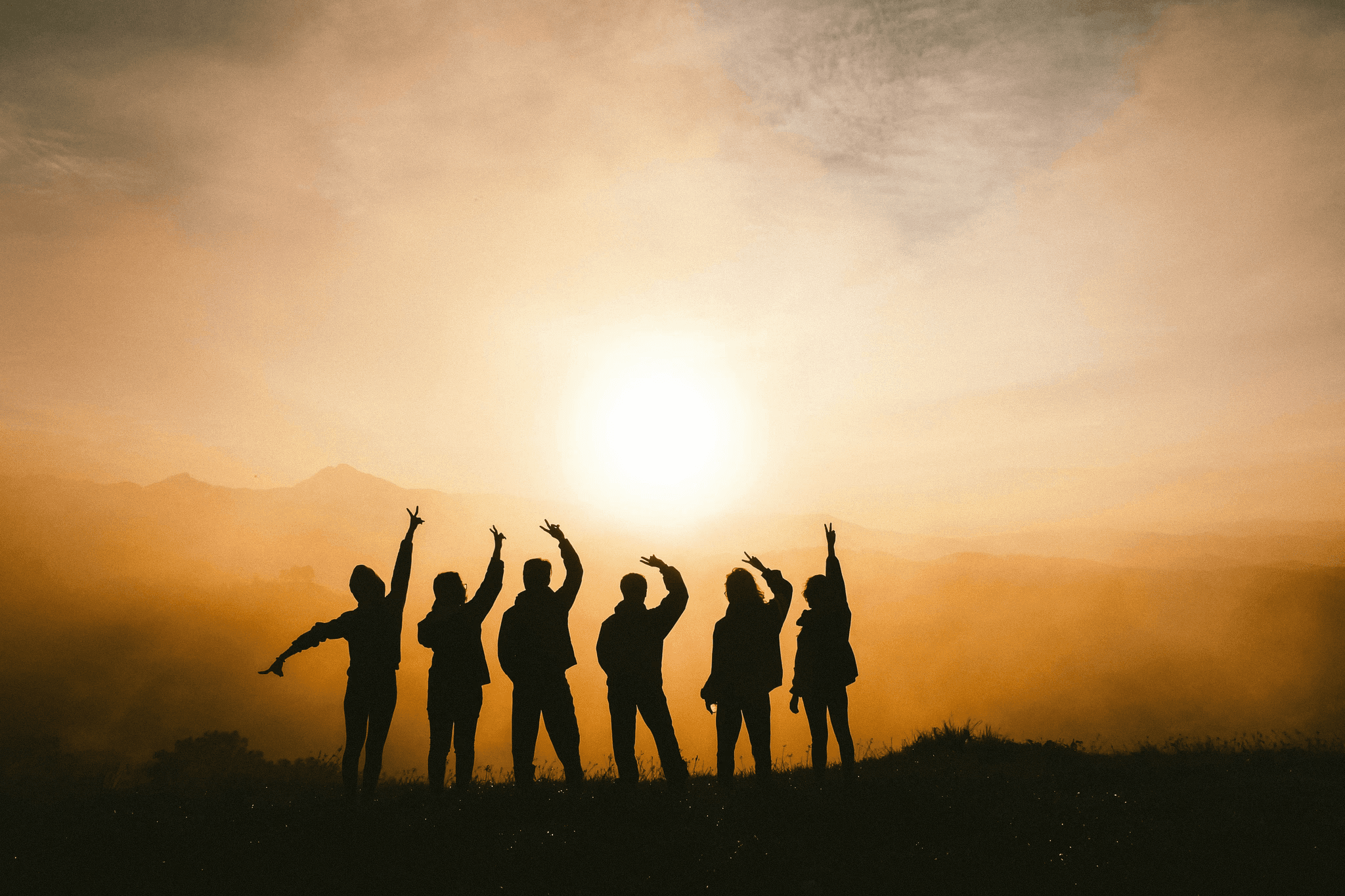 Group of people silhouetted at sunset, representing connection, support and community