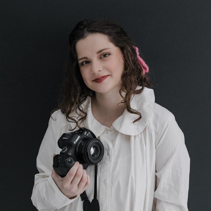 Gracie Wall holding a camera at Revelator Studio, a natural light photography studio in Shreveport, offering a versatile and creative space for photographers and videographers.