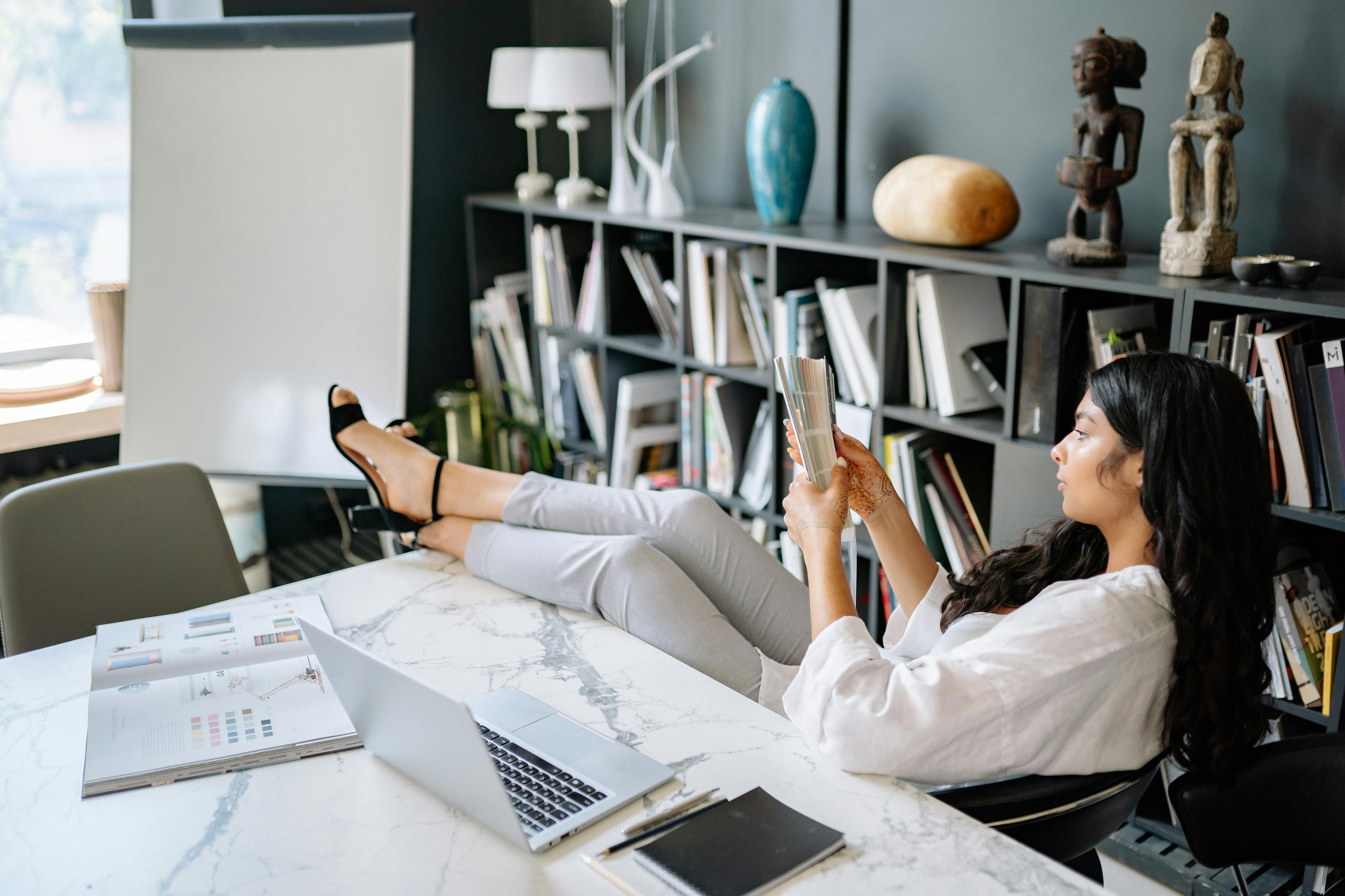 Professionista seduta in ufficio con postura rilassata ma distante, metafora di un ruolo lavorativo che non valorizza competenze e potenziale della persona.