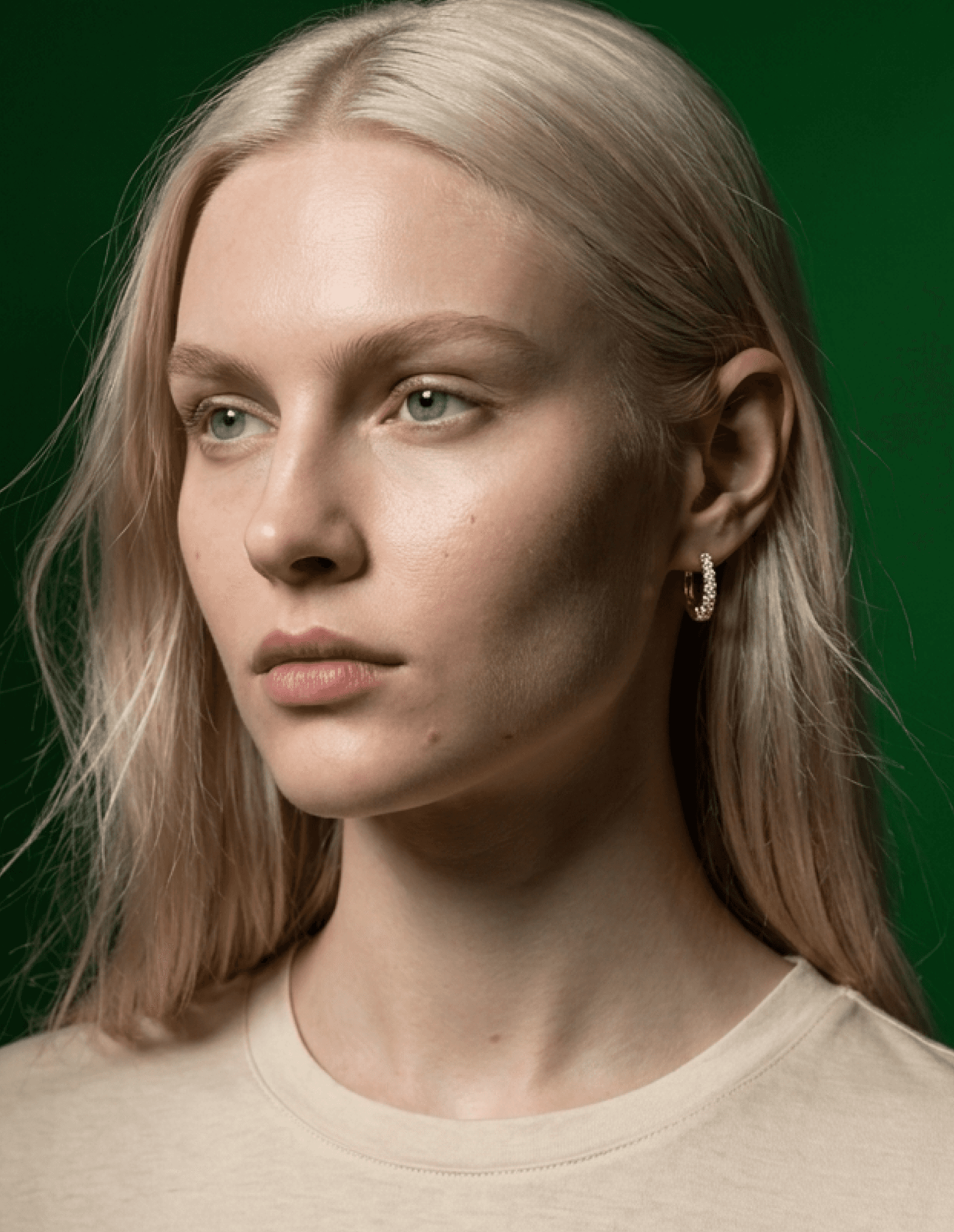 Blonde model wearing gold earrings in a minimal studio lighting setup