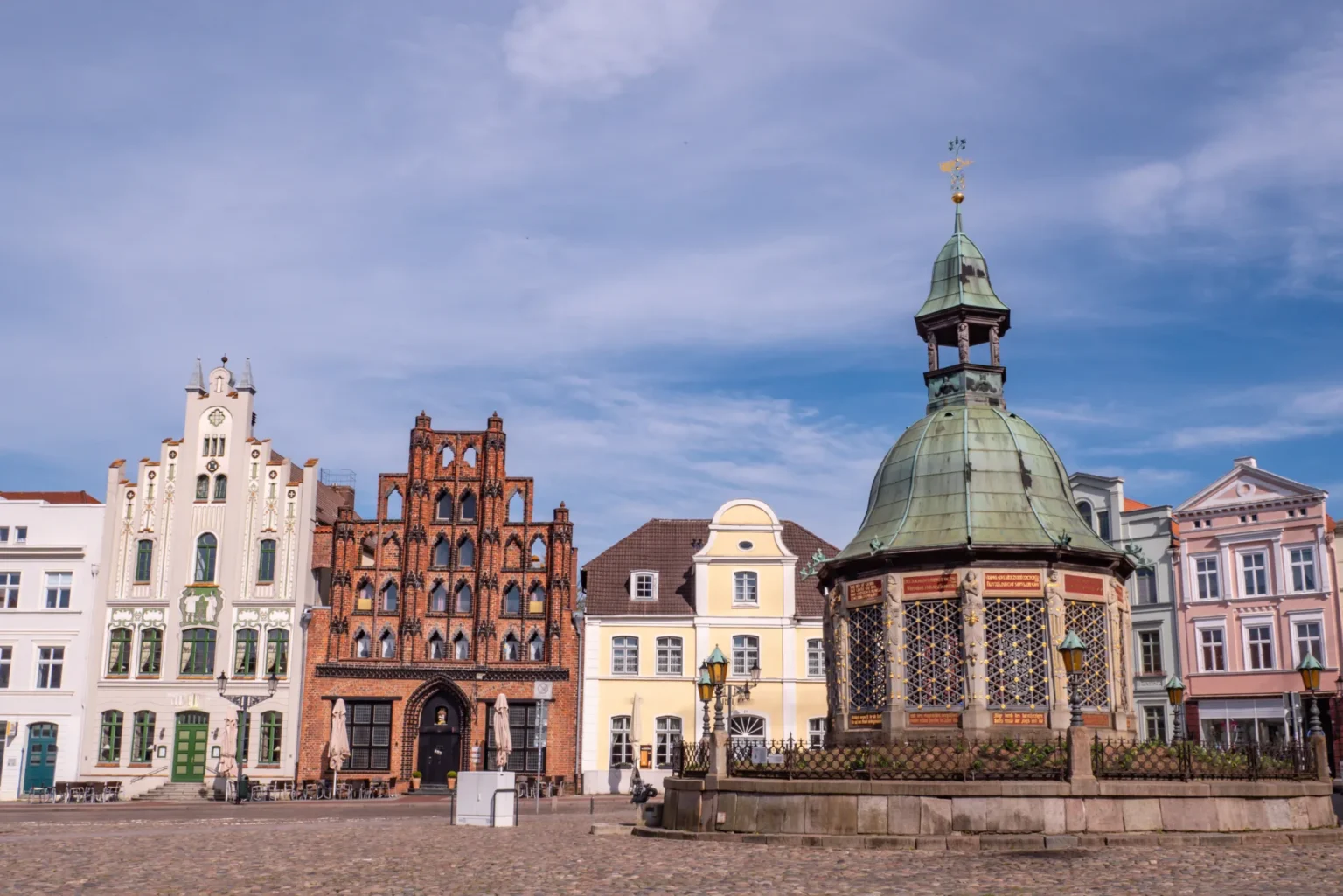 Historische Gebäude mit vielfältiger Architektur unter einem blauen Himmel, mit einer markanten Kuppelstruktur.