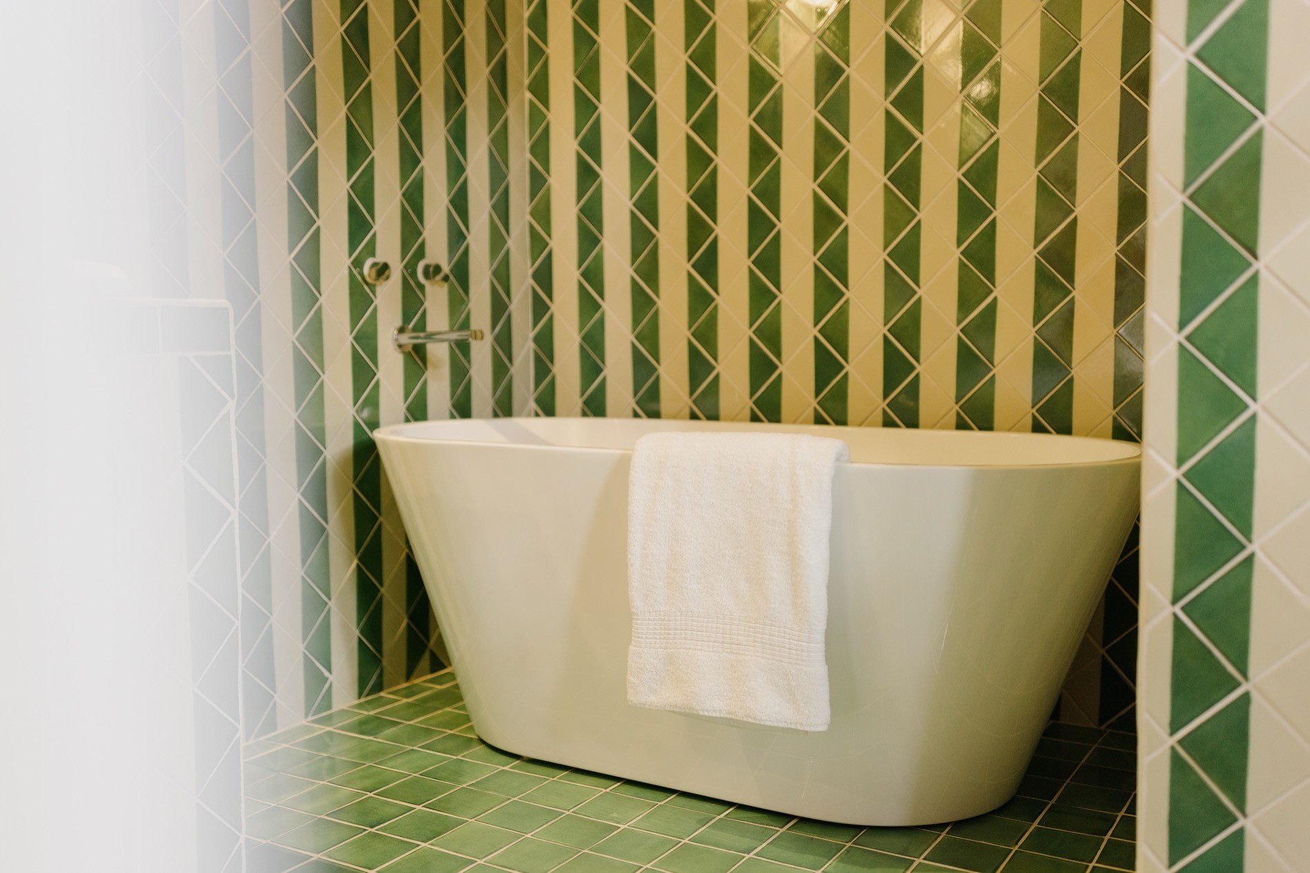 Freestanding soaking tub with handcrafted green and cream Mexican tile at La Residencia