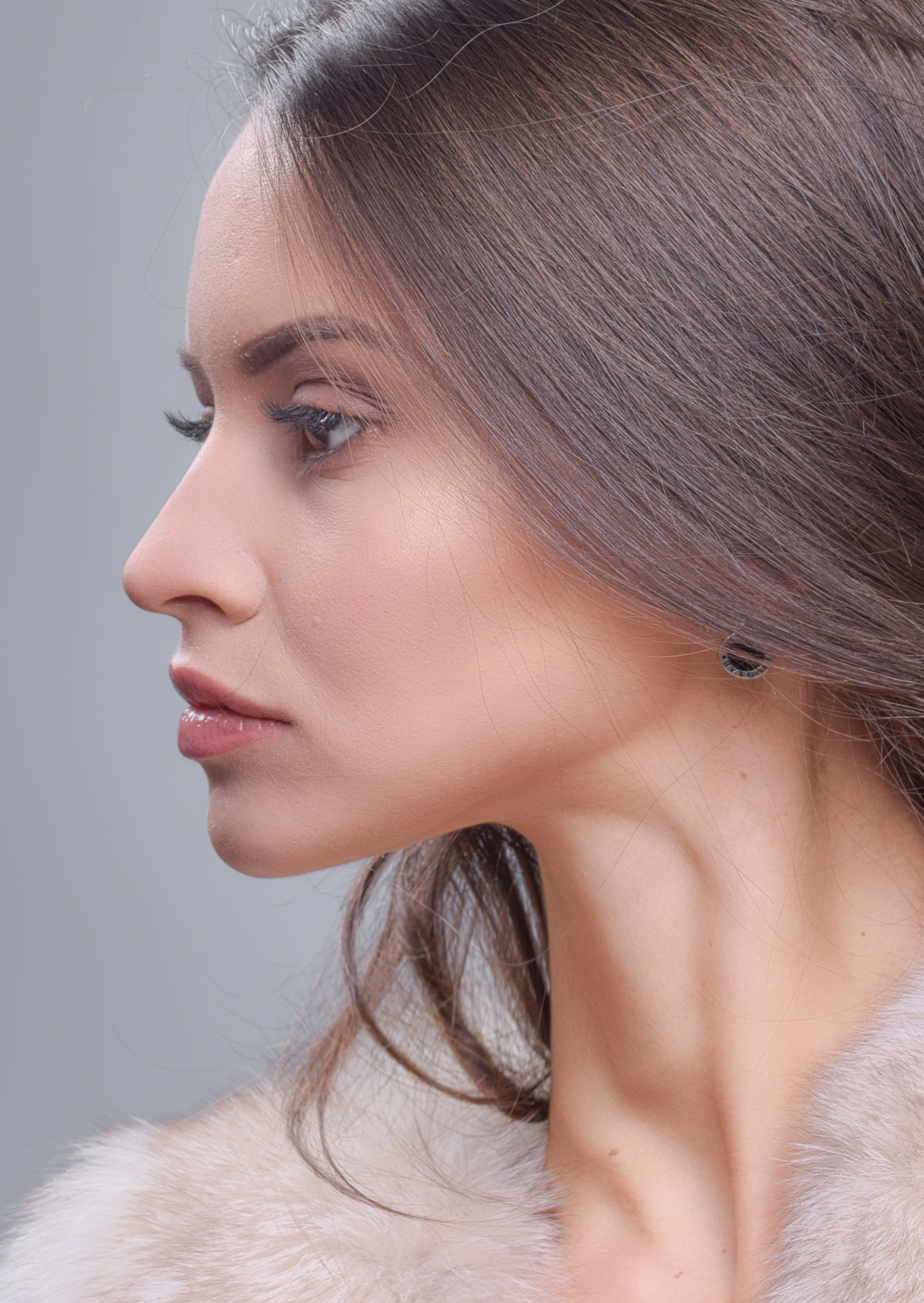 a woman wearing a fur coat and a pair of earrings