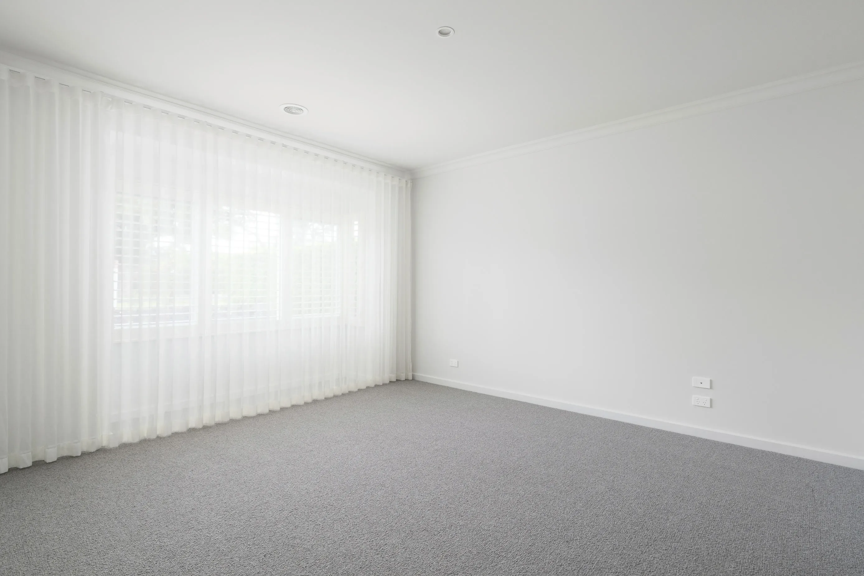 Bundoora bedroom with sheer curtains, grey carpet and crisp white walls