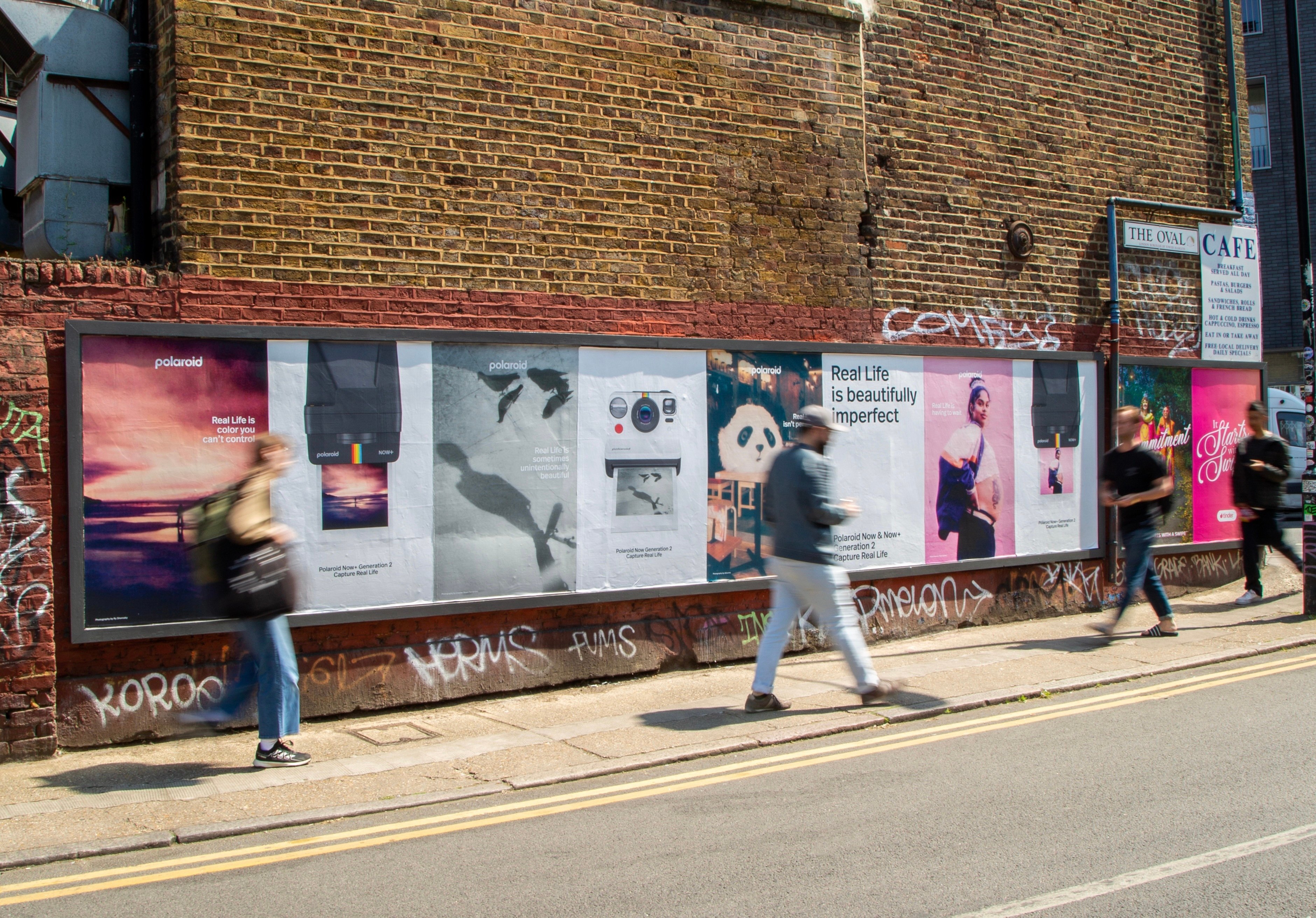a man walking down a street past a large poster