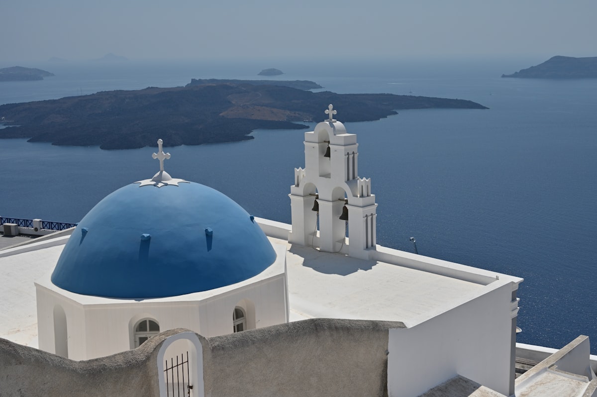 Blue-domed Santorini church above whitewashed walls facing the open Aegean caldera