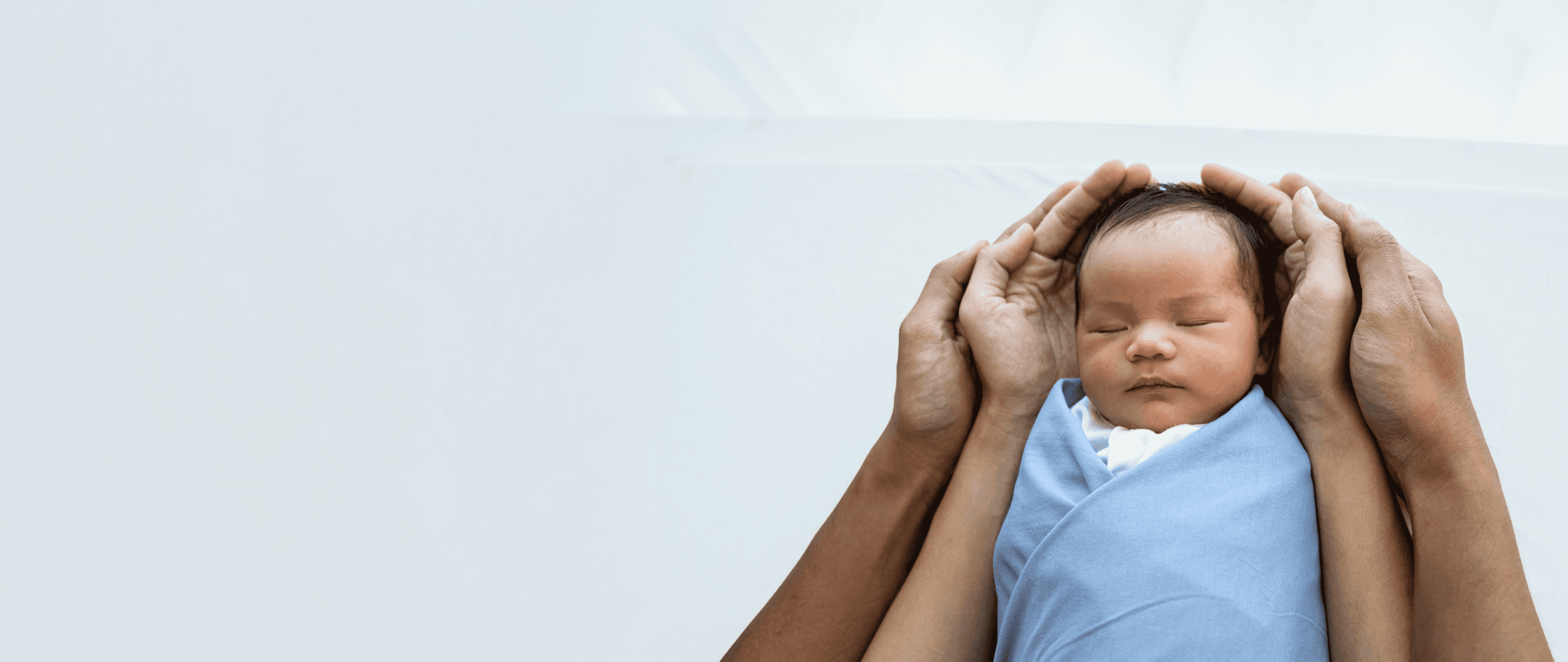 Parent's hands around a newborn baby