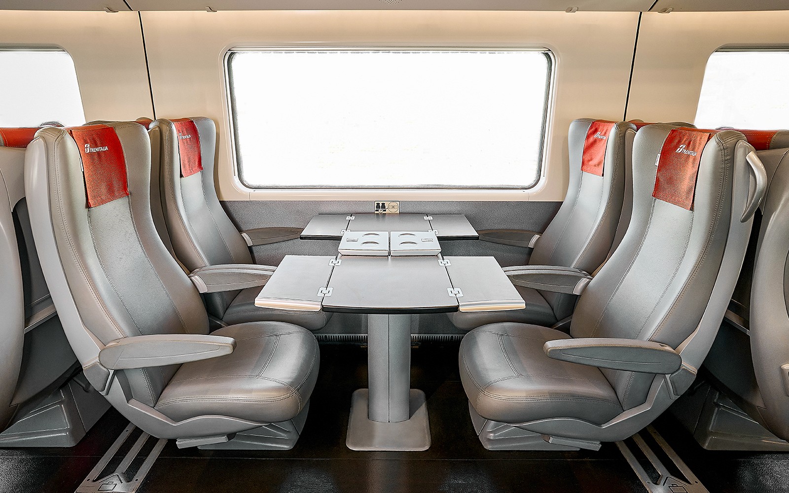 Kursi kelas standar Trenitalia dengan meja di bagian dalam kereta.