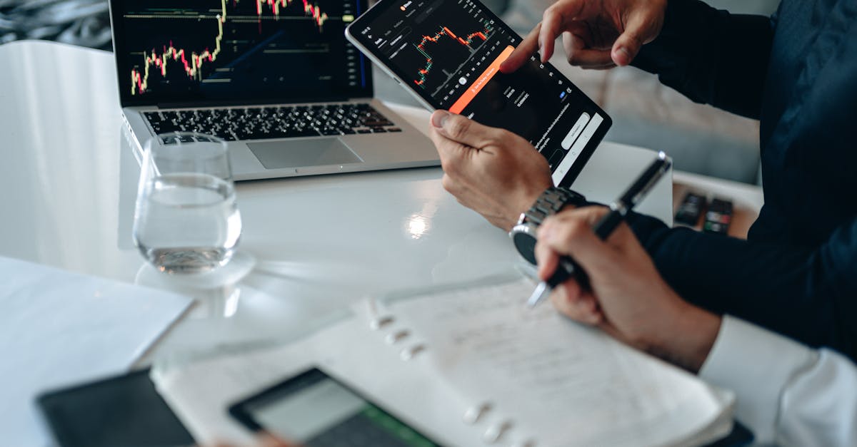 Business professionals reviewing financial charts on digital devices in a modern office setting.