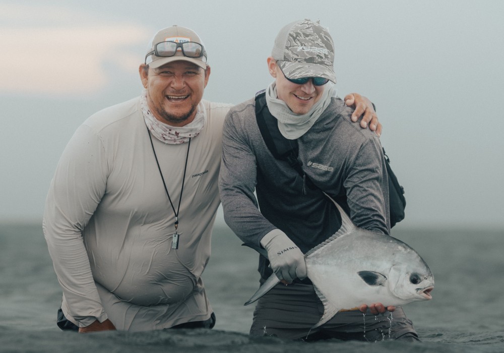 Marlon and saltwater angler holding a caught permit on the flats