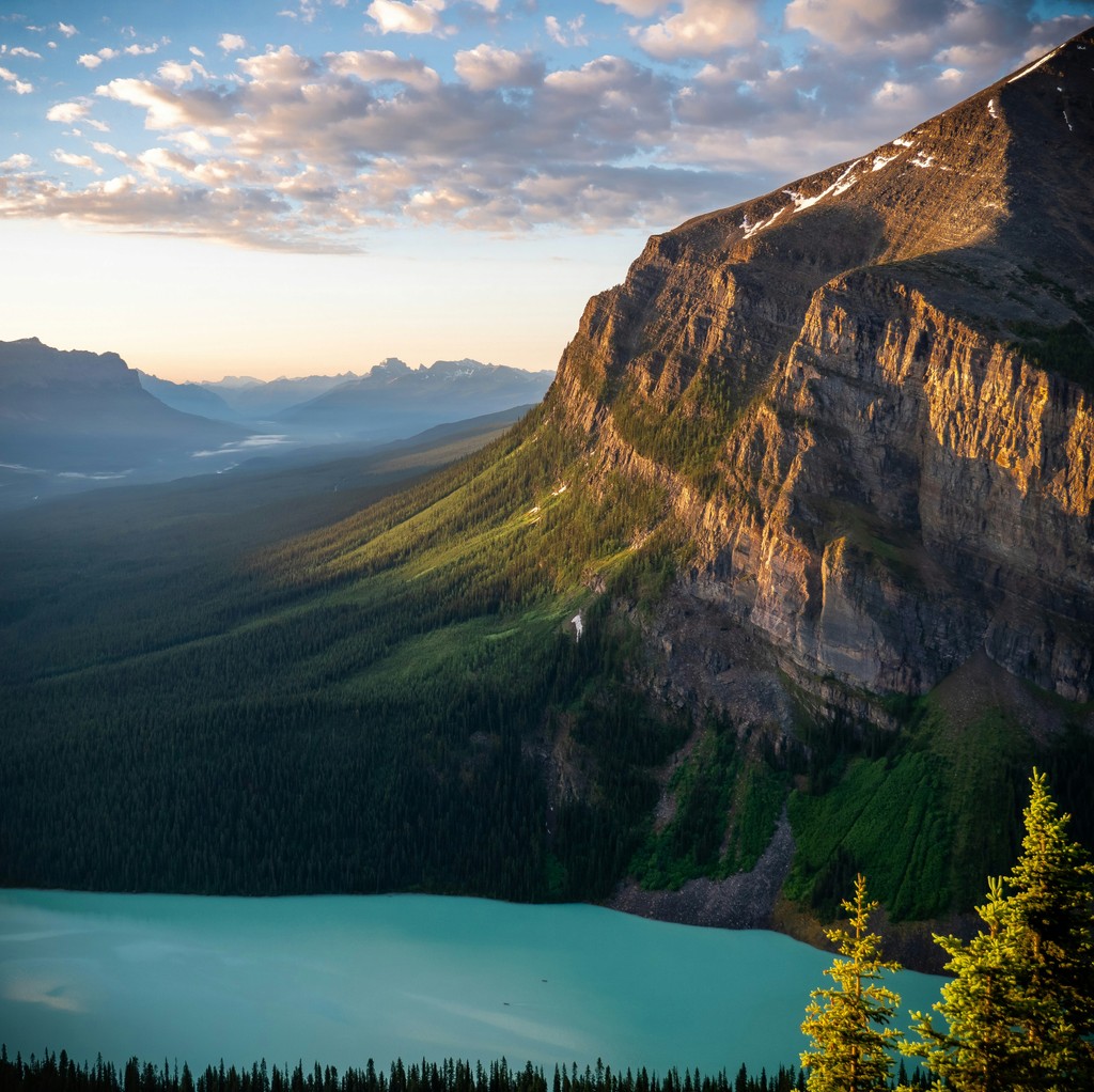 Sunlight hitting a mountain next to an aqua-colored lake