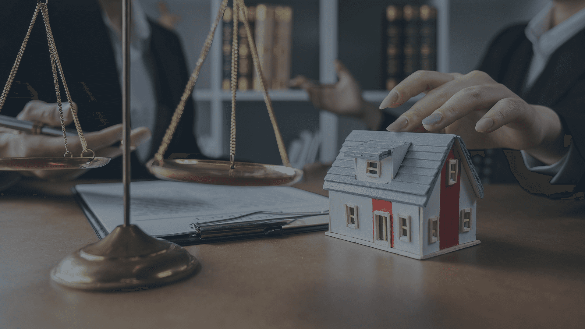 Attorney hands positioned over a model home with legal books in the background, representing estate planning, wills, and trusts services at Lamb & Lamb, P.C. in Salem, MA