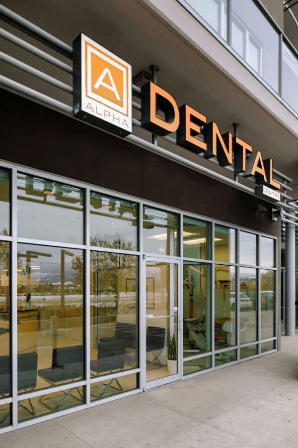 Exterior of Alpha Dental Centre with glass doors and large windows.