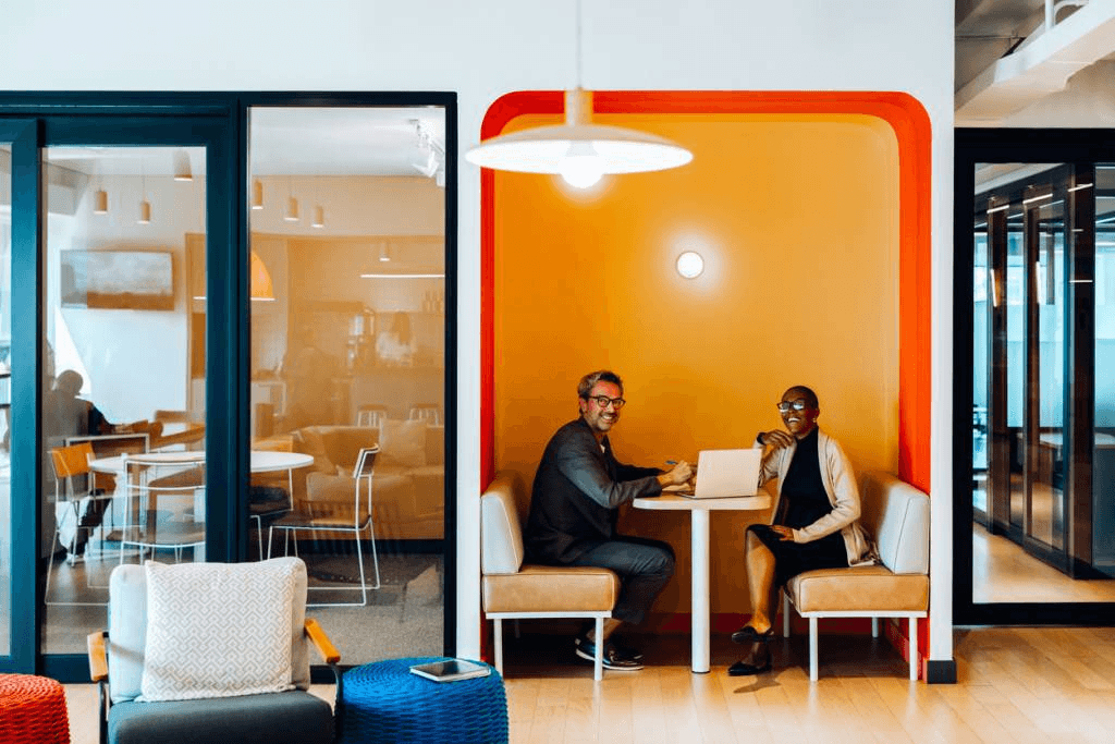 Modern office space showing two colleagues sitting in a vibrant huddle space