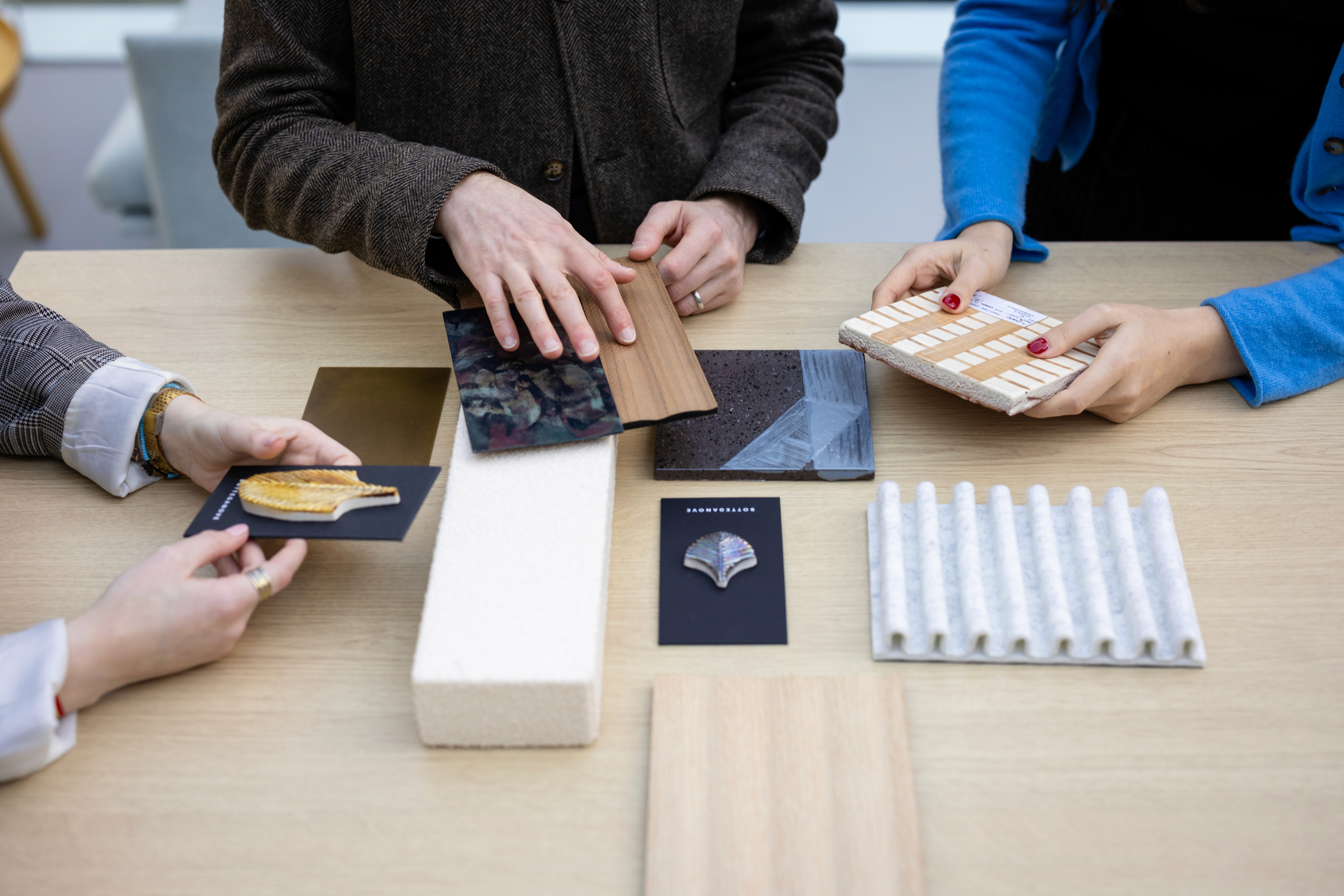 people sitting on chair in front of table while holding pens during daytime
