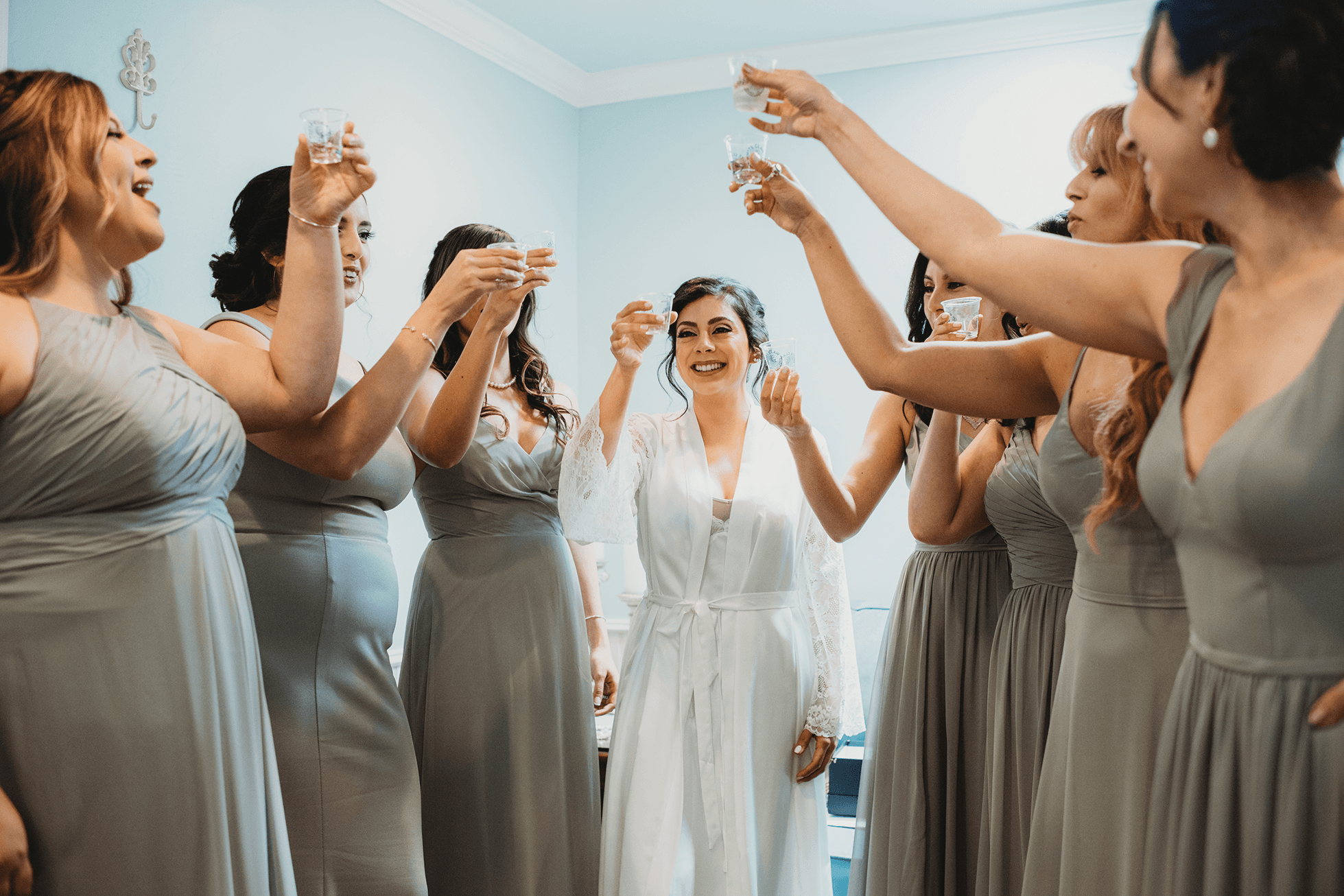 Bride cheers with bridesmaids in bridal suite before ceremony