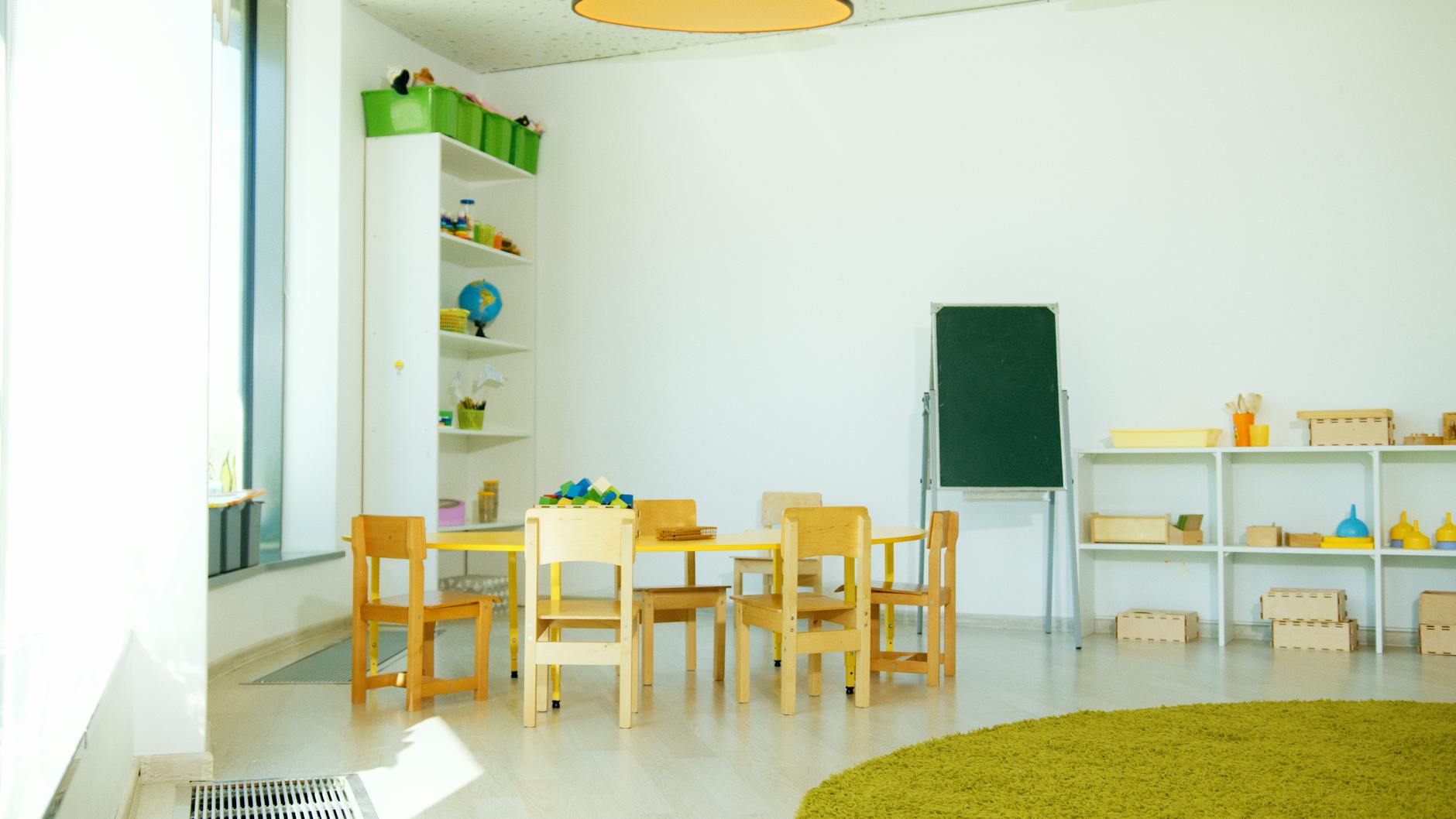 An educator arranging tactile sandpaper letters on a child-sized table to start the montessori method of teaching.