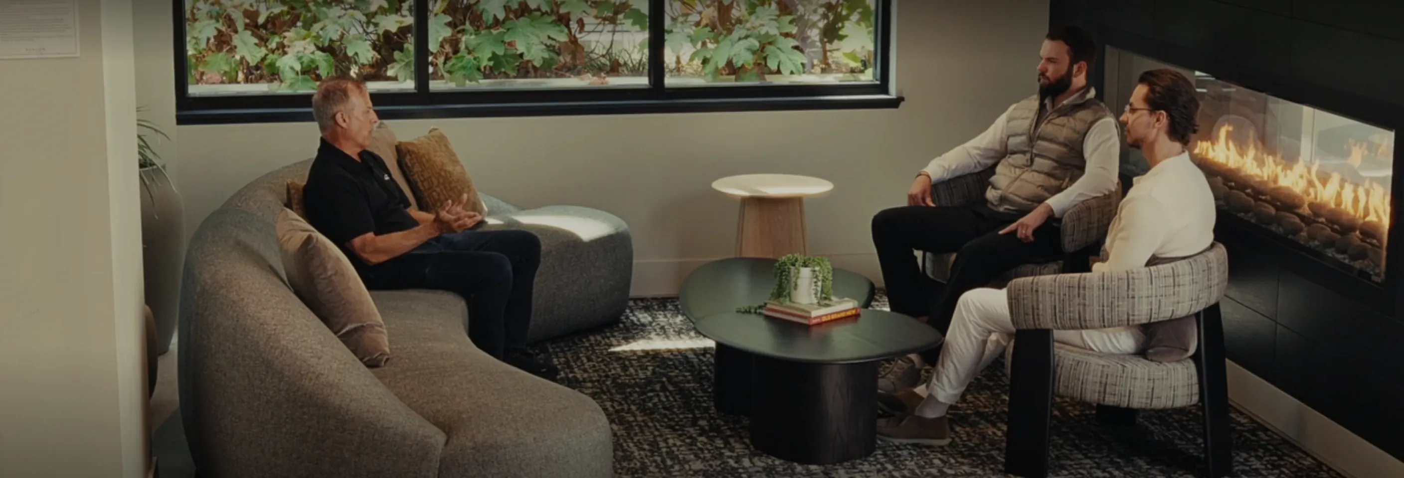 Two people talking in a lounge beside a fireplace