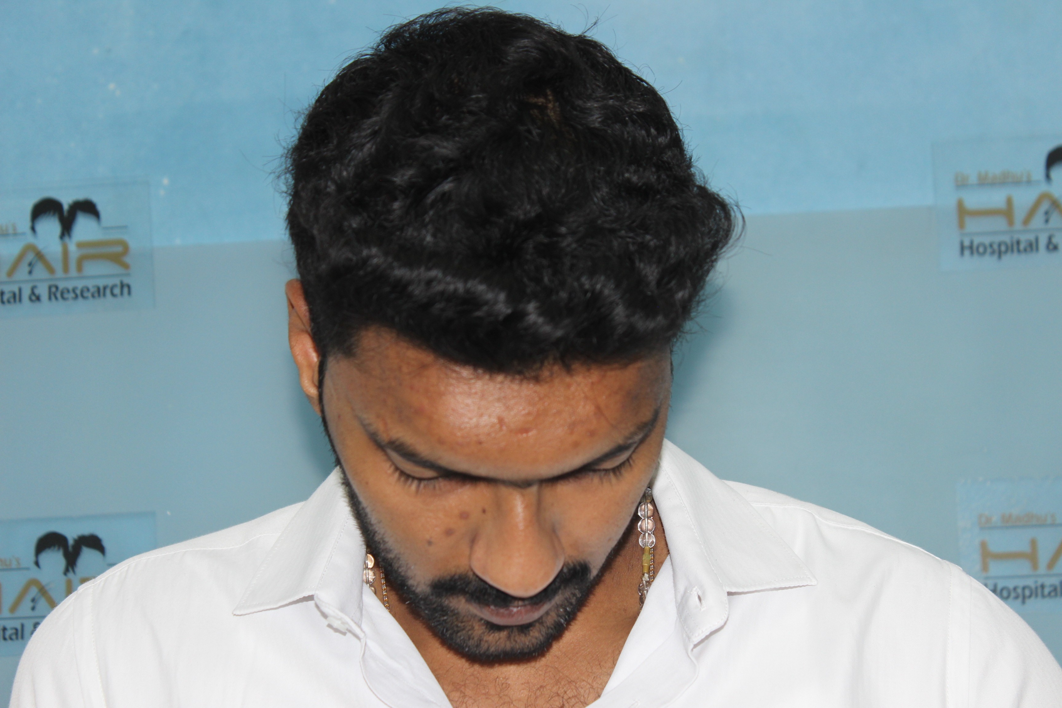 Person with red curly hair in flowing fabric on pale landscape.