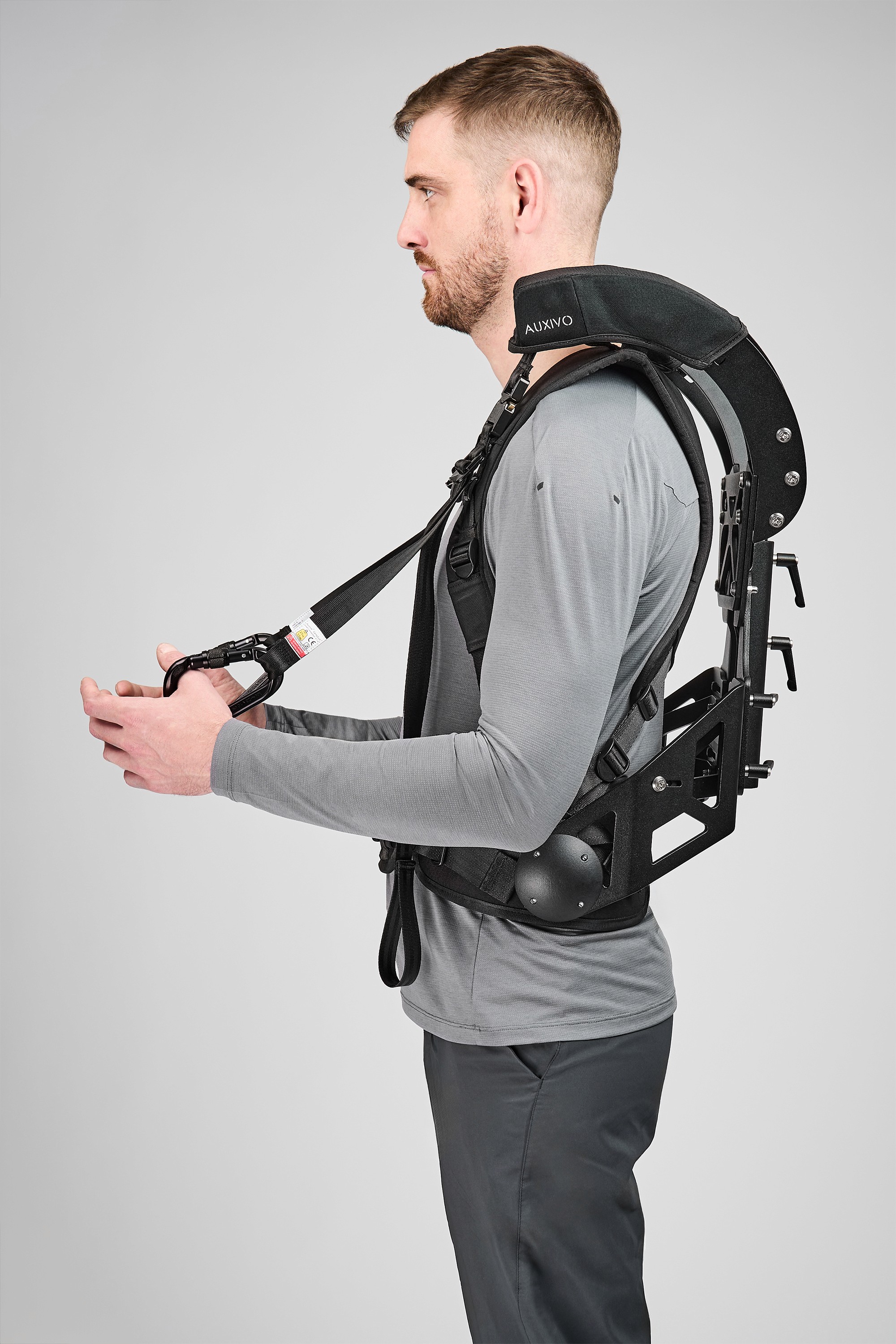User wearing an Auxivo CarrySuit exoskeleton with front assistance strap.