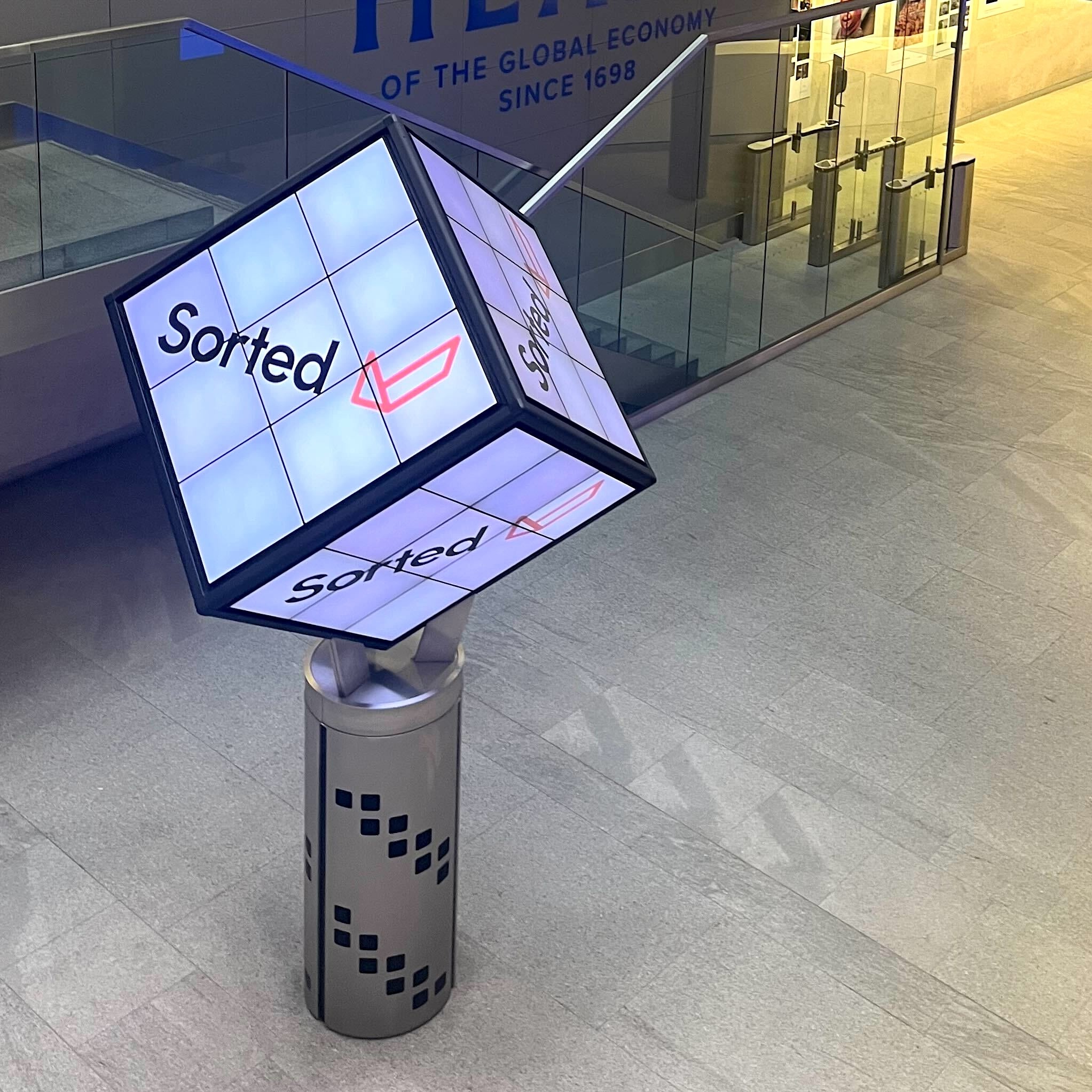 Illuminated cube display with the Sorted logo in a modern indoor setting