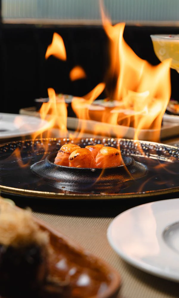 Sushi flambéed at the table on a black plate