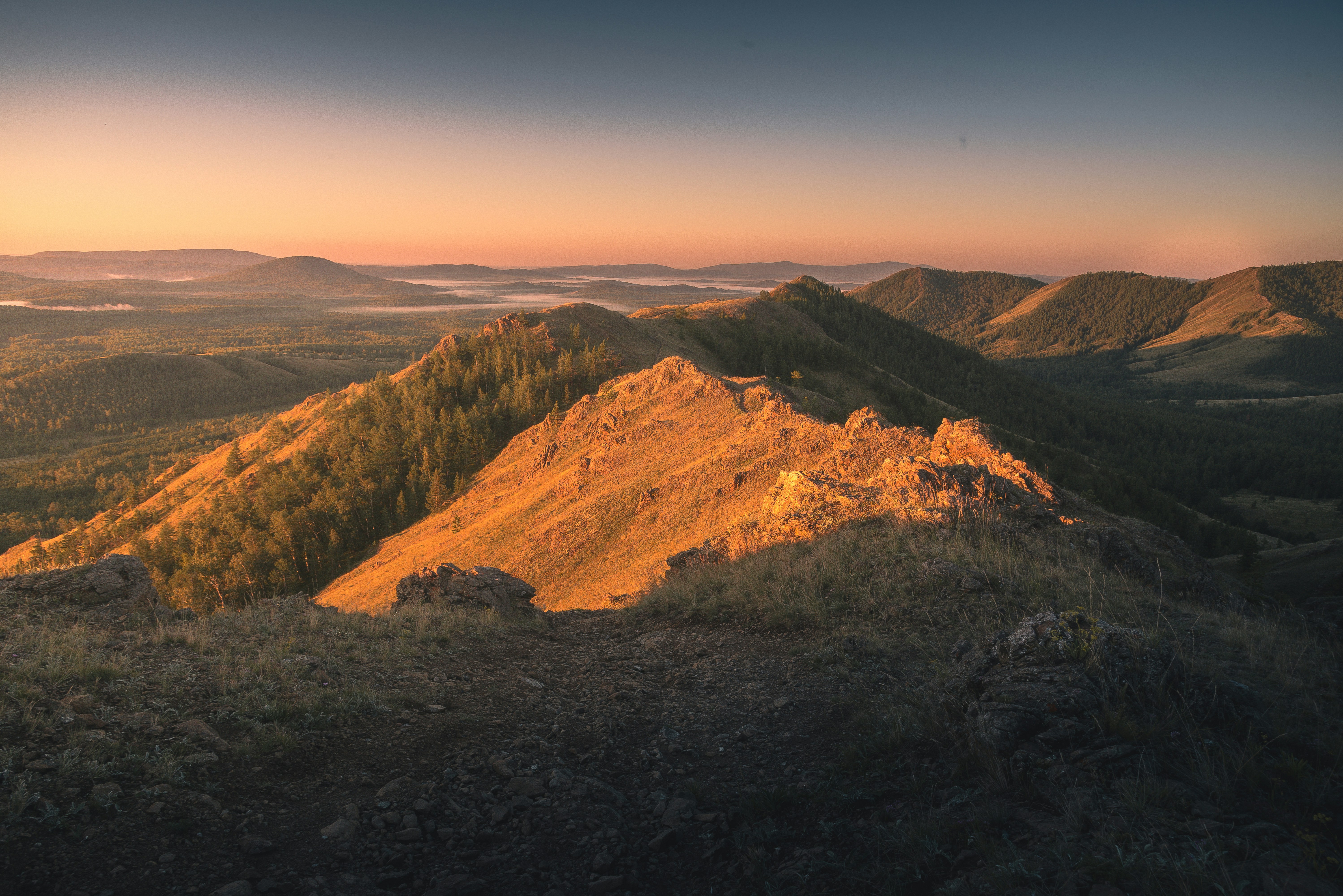 Golden mountain peaks at sunrise with mist in valleys