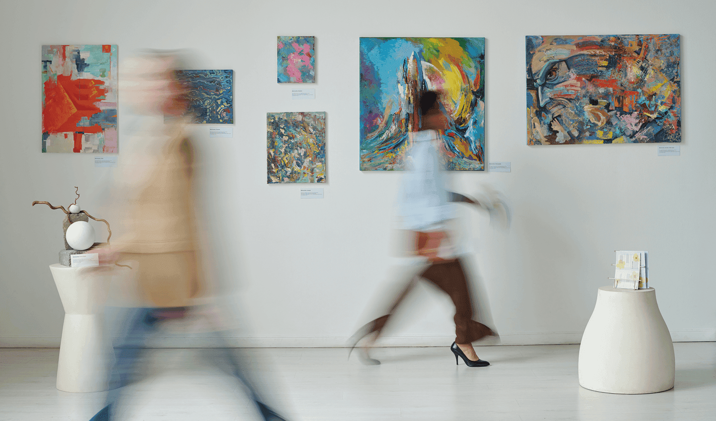Two people walking past colourful abstract paintings in a gallery space, representing Ireland’s vibrant art and culture.