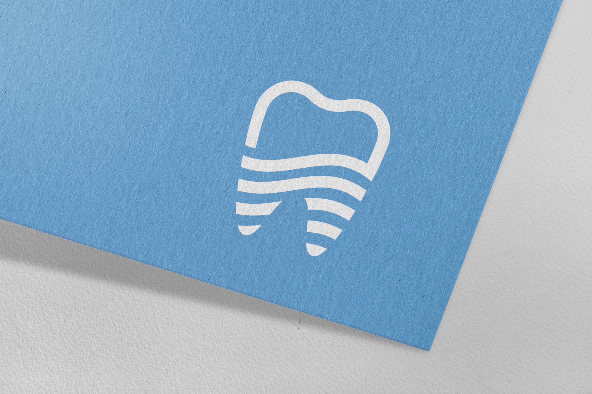 這張圖像展示了東樂牙醫診所的標誌,標誌為白色牙齒圖案,內有波浪紋,背景為淺藍色紙張。