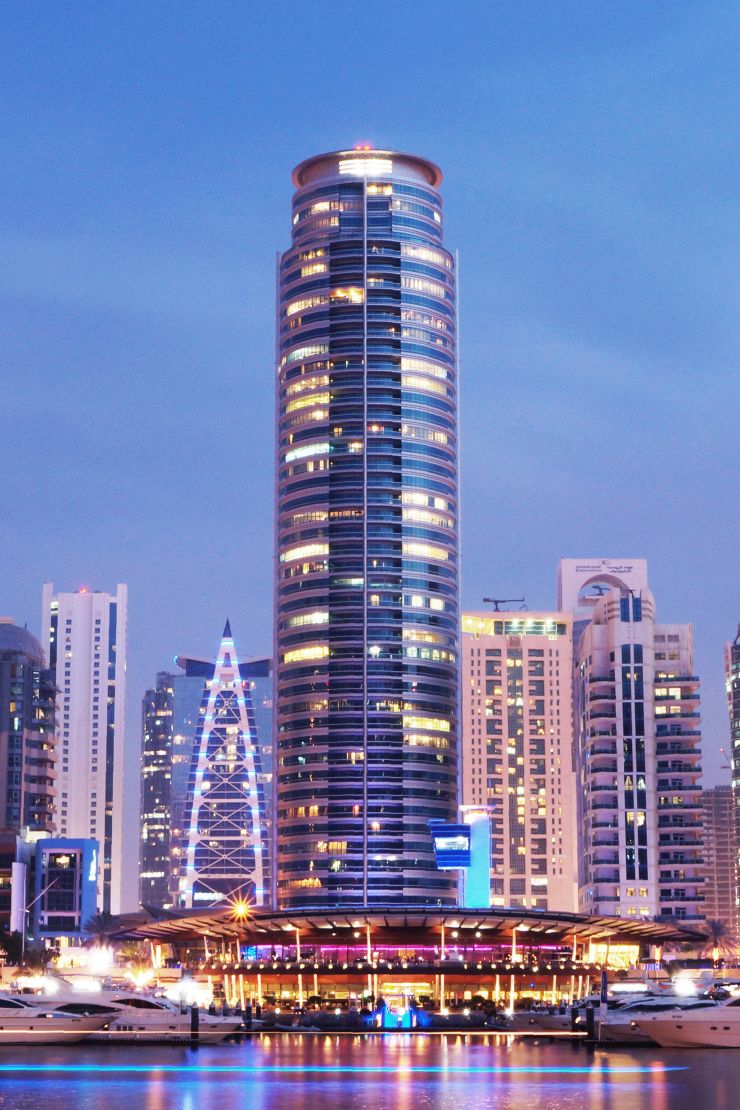 Night view of Horizon Tower illuminated over the marina, featuring high-end apartments for rent and sale.