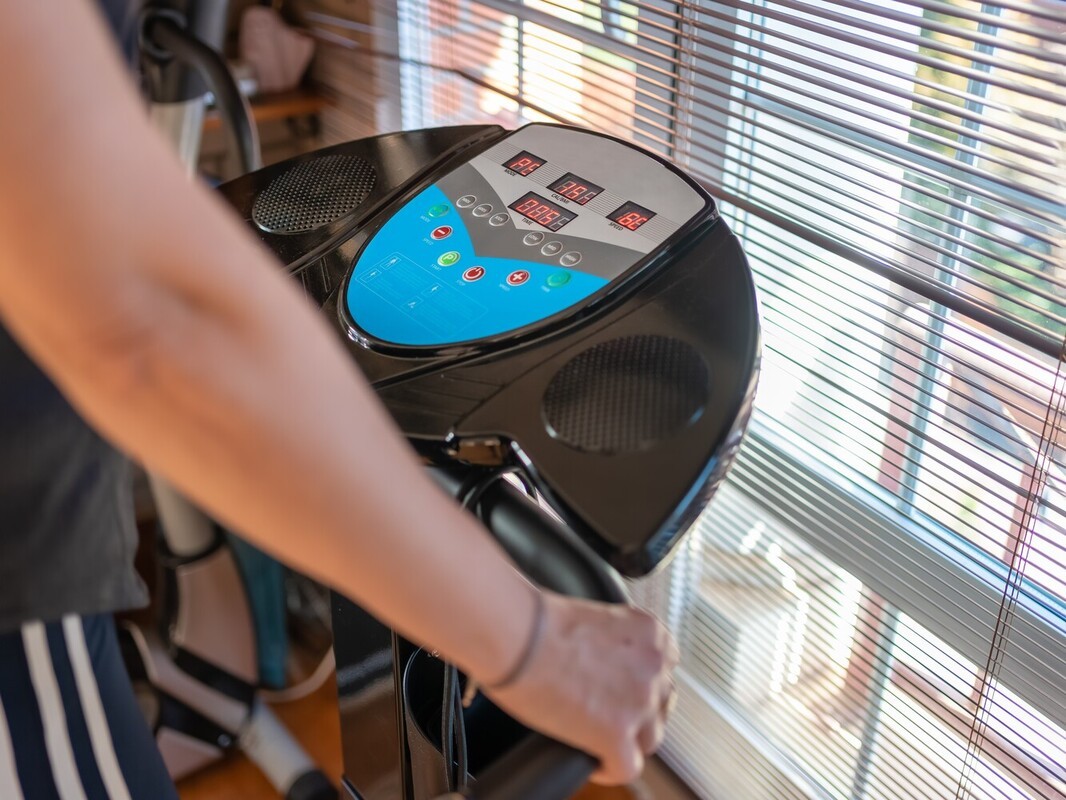person standing on a vibration plate, showing how to use a vibrating machine to lose weight at home