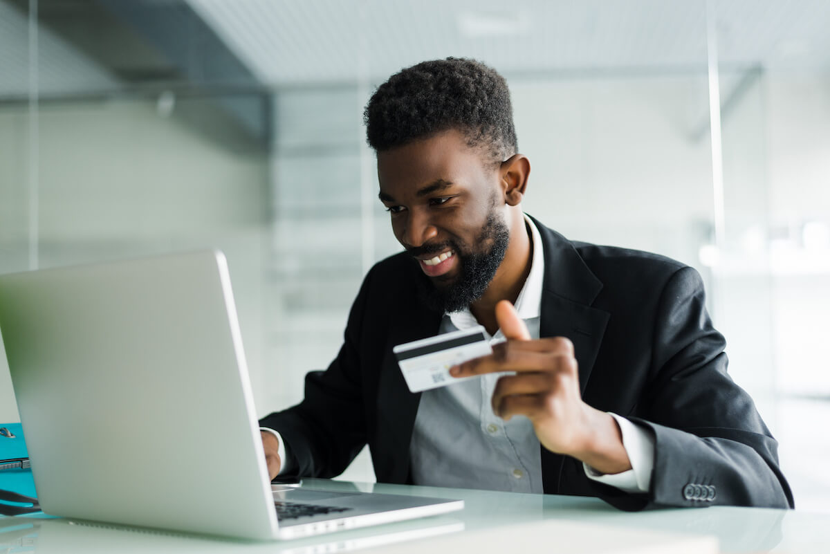 Smiling man purchasing online and holding his credit card 