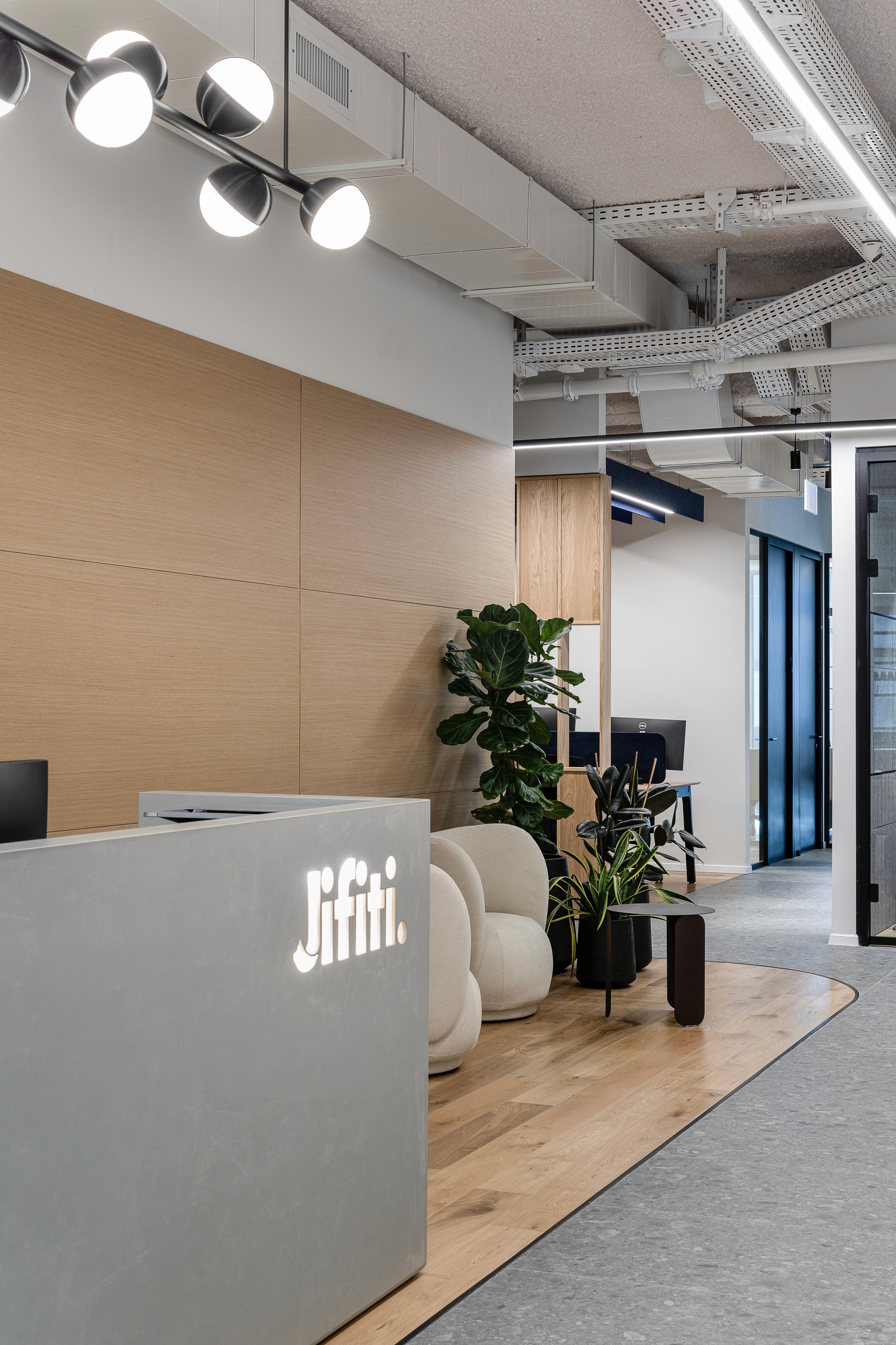 מבואה ודלפק קבלה: משחקי נפחים וטקסטורות בין הבטון היצוק לחיפוי העץ המעוגל, המגדירים את הכניסה למשרדי הפינטק המודרניים.