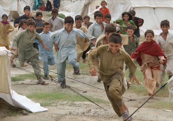 Three children jumping in burlap sacks during a race.