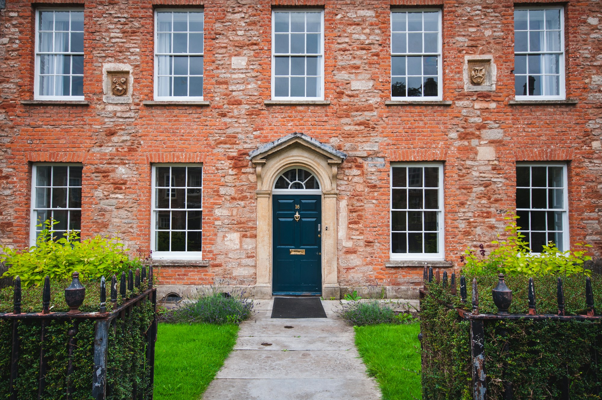 A Georgian red-brick office with a dark front door and clipped hedges