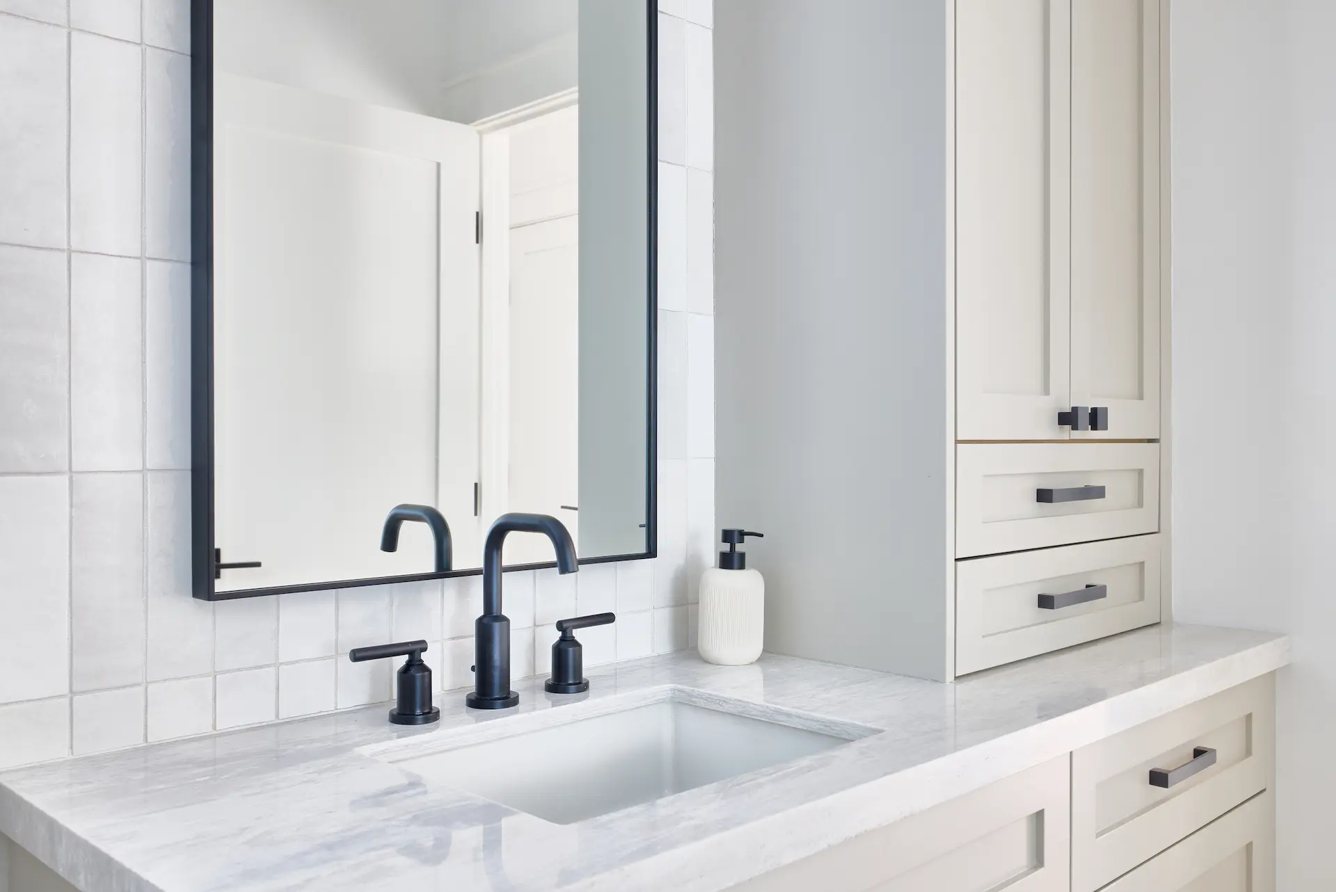Close-up of the bathroom vanity in ADU Orange, highlighting contemporary black fixtures against a backdrop of muted colors. Photo by Todd Huge.