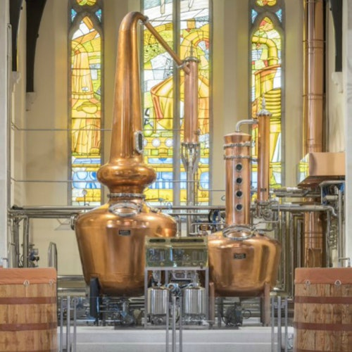 Copper distillation equipment inside a room with stained glass windows.