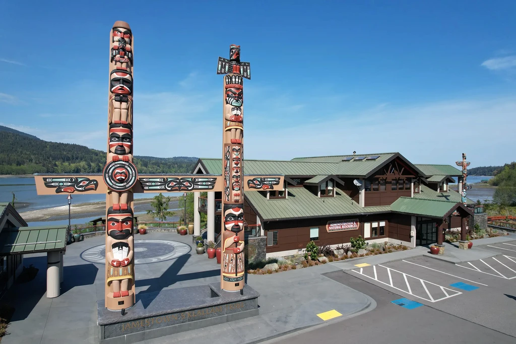 The front of the Jamestown S'Klallam Tribe's Administration and Natural Resources Department building. Two totem poles are to the left of the building.
